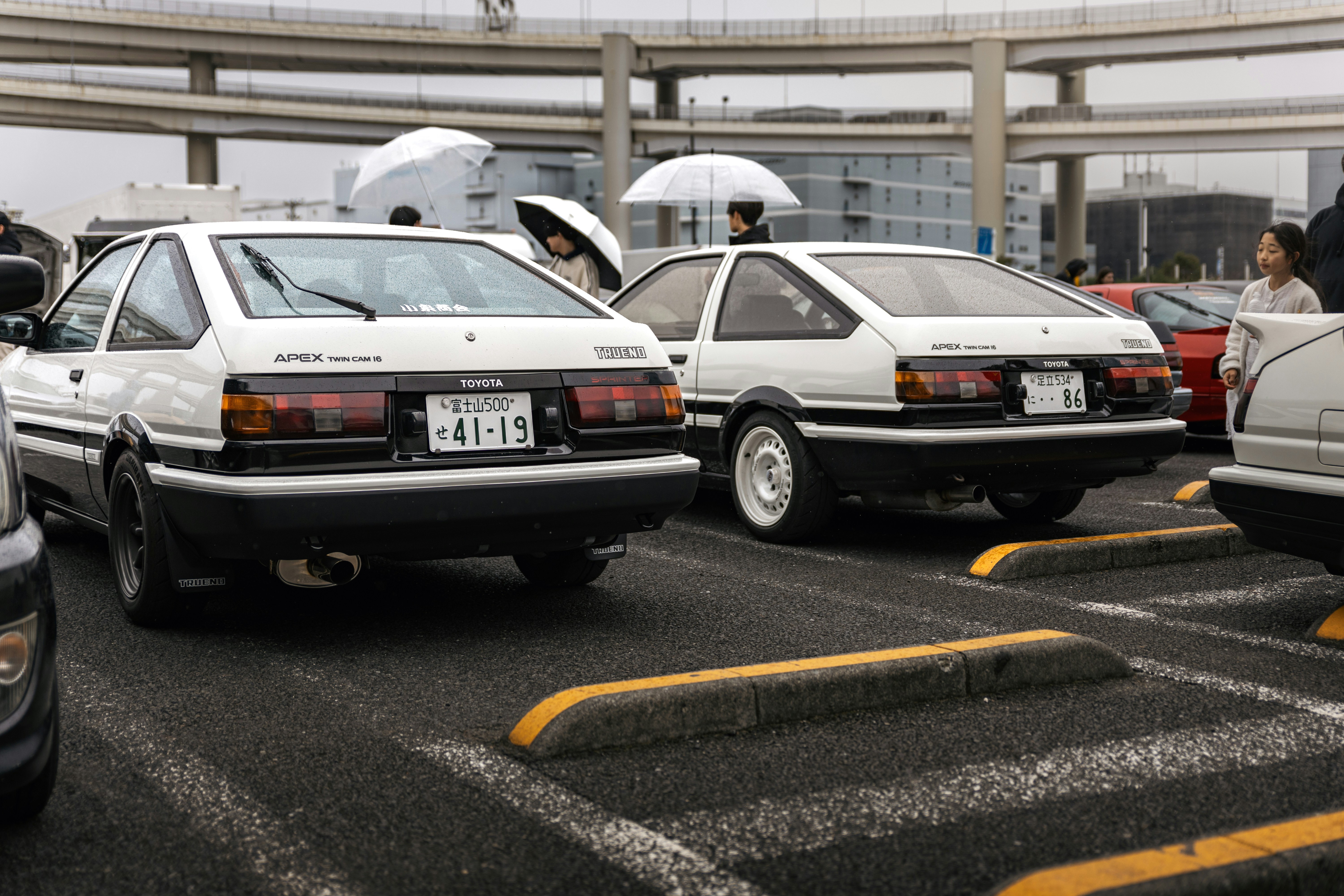 Two white toyota ae86 cars parked in lot