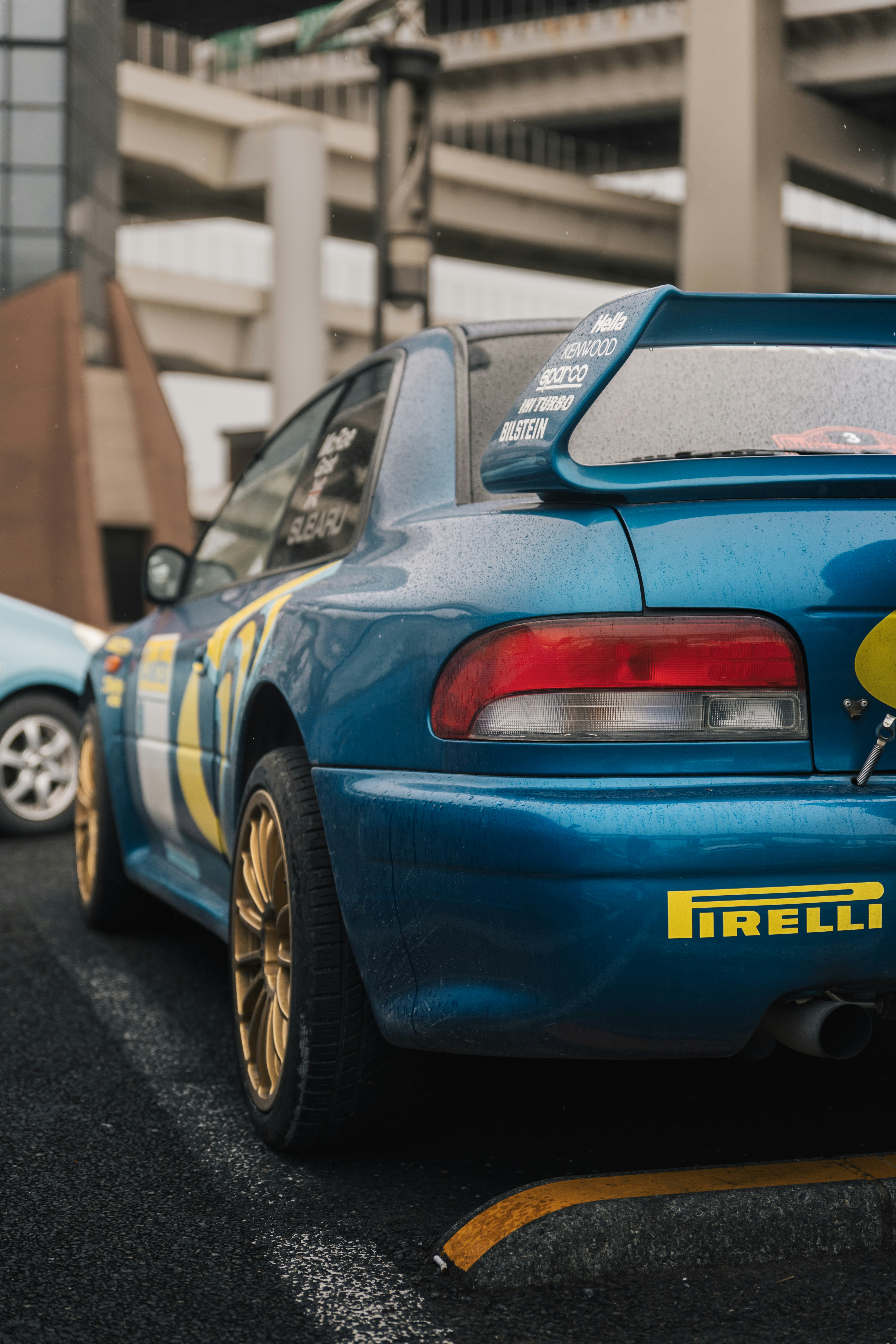 Blue rally car with gold wheels parked on street
