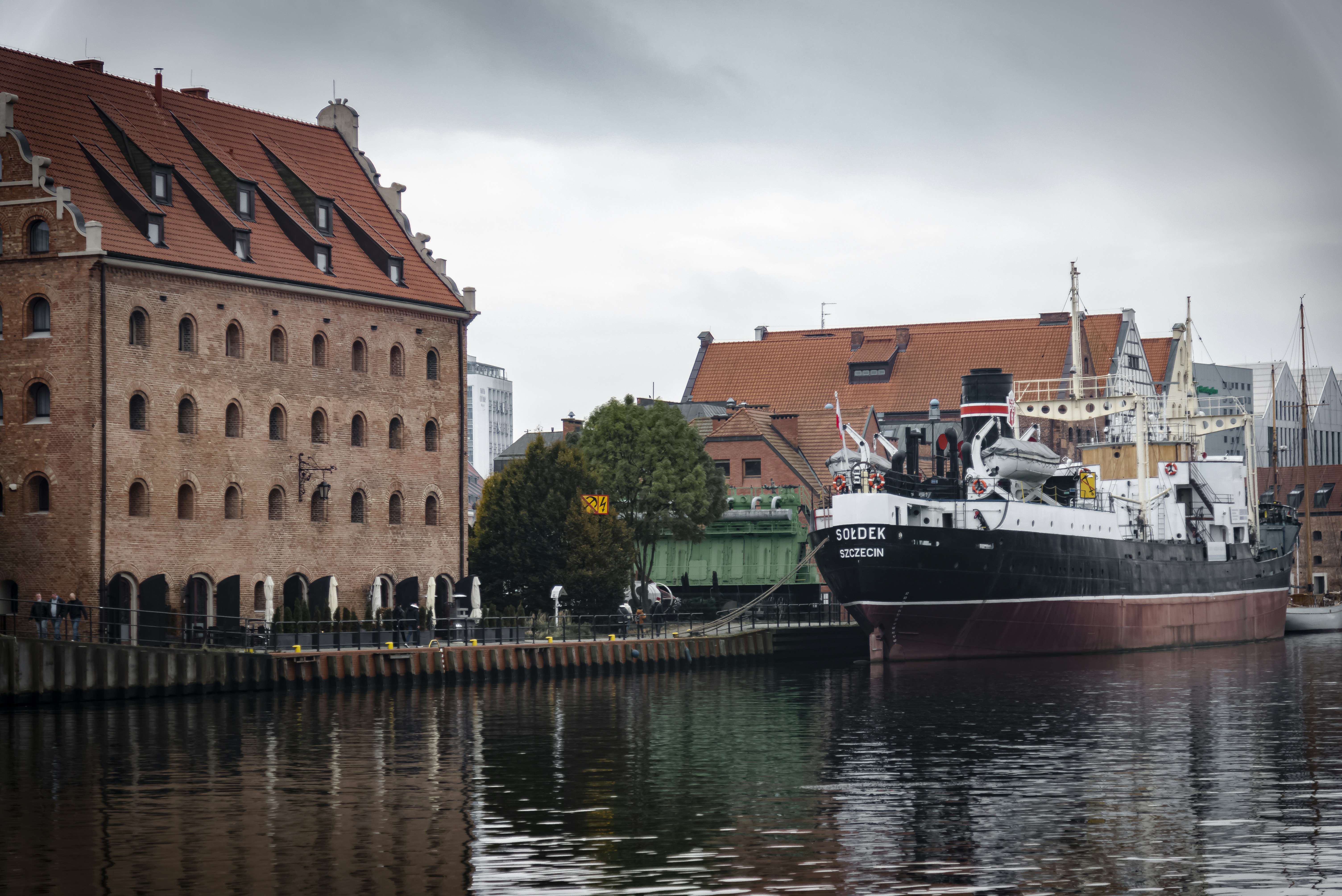Ship docked beside historic brick buildings on canal.