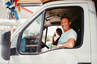 Man driving a white van gives a thumbs up.