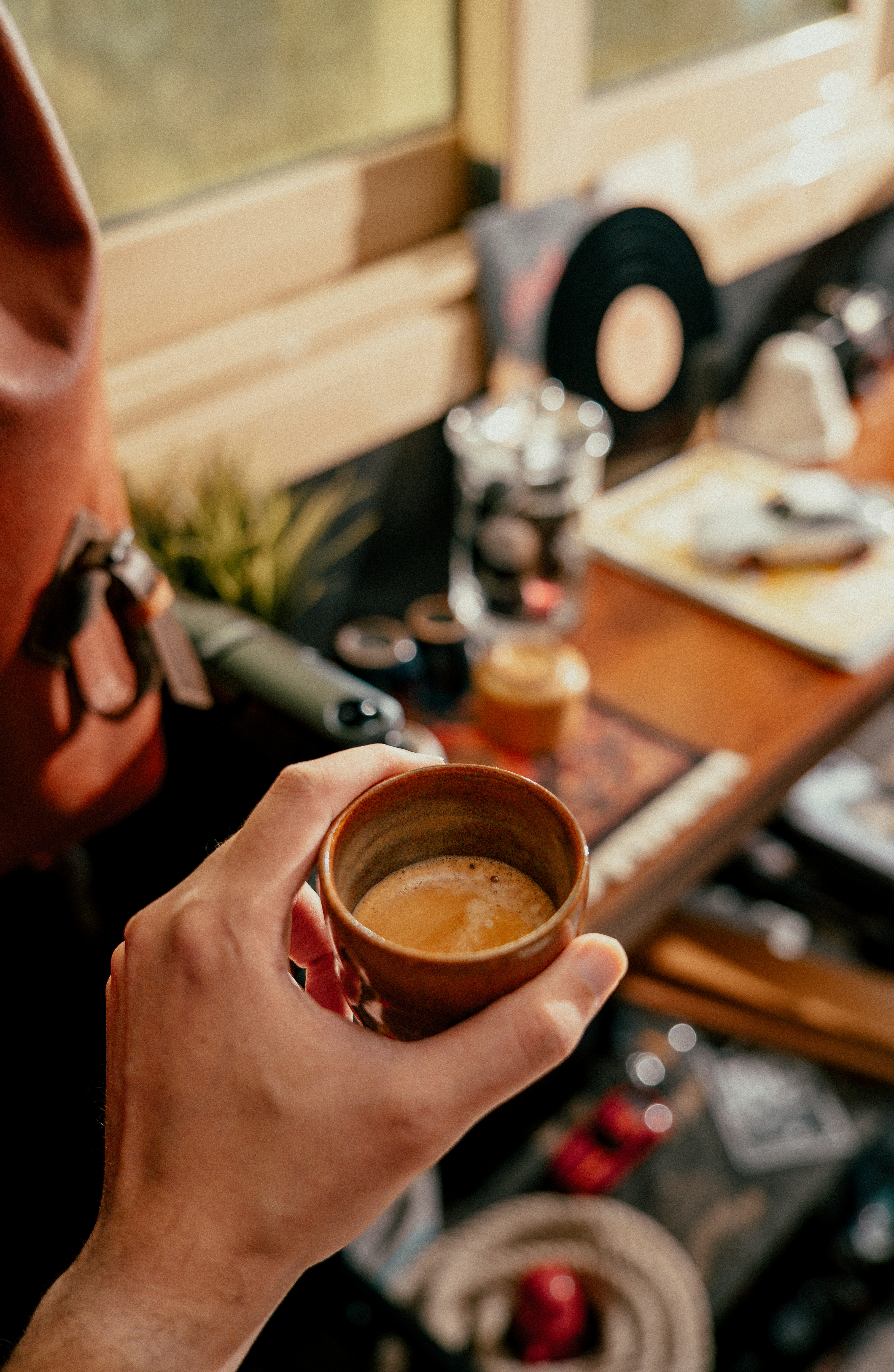La mano sostiene una pequeña taza de café casi espumoso.