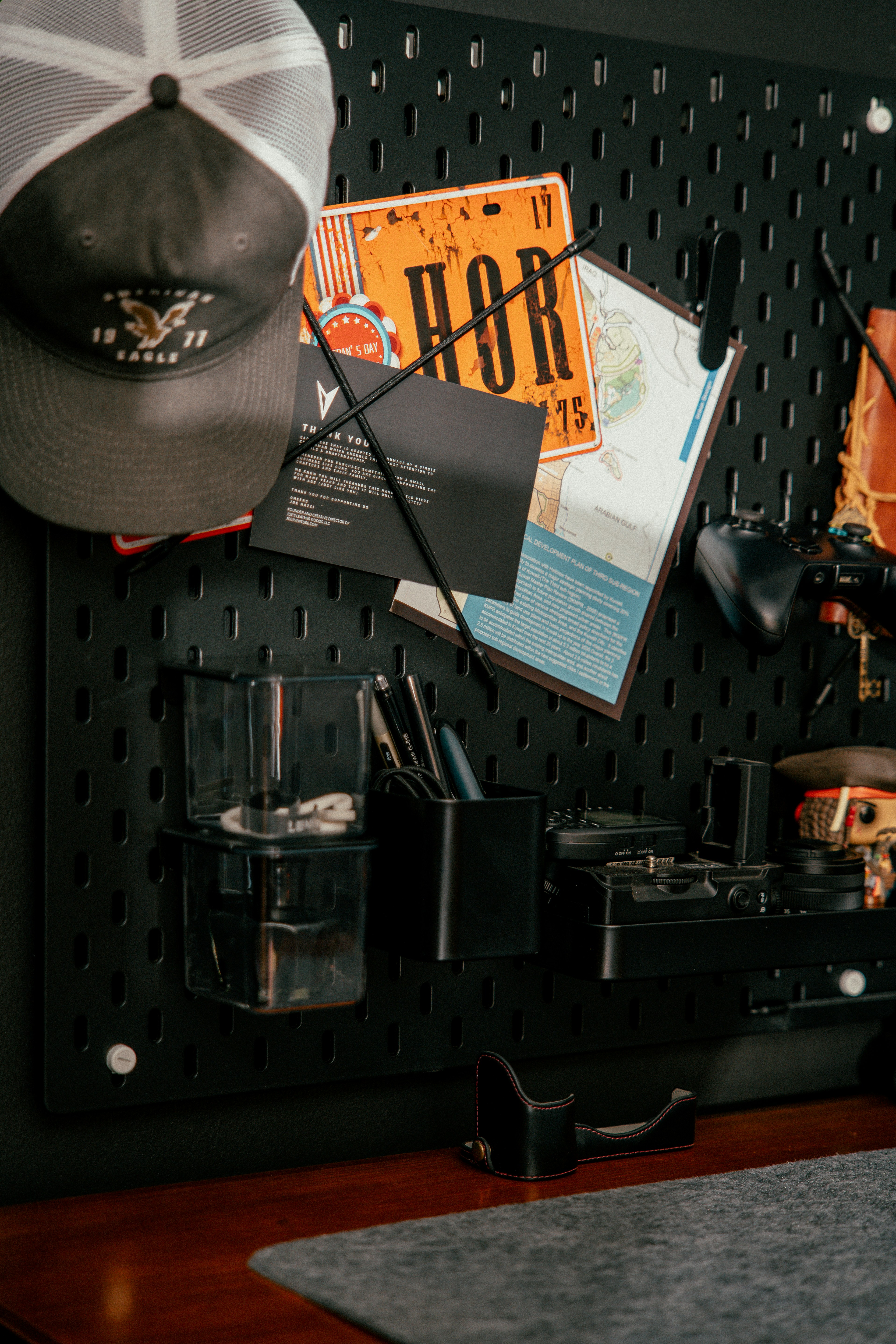 Organizador de tablero perforado con sombrero, mapa y herramientas.