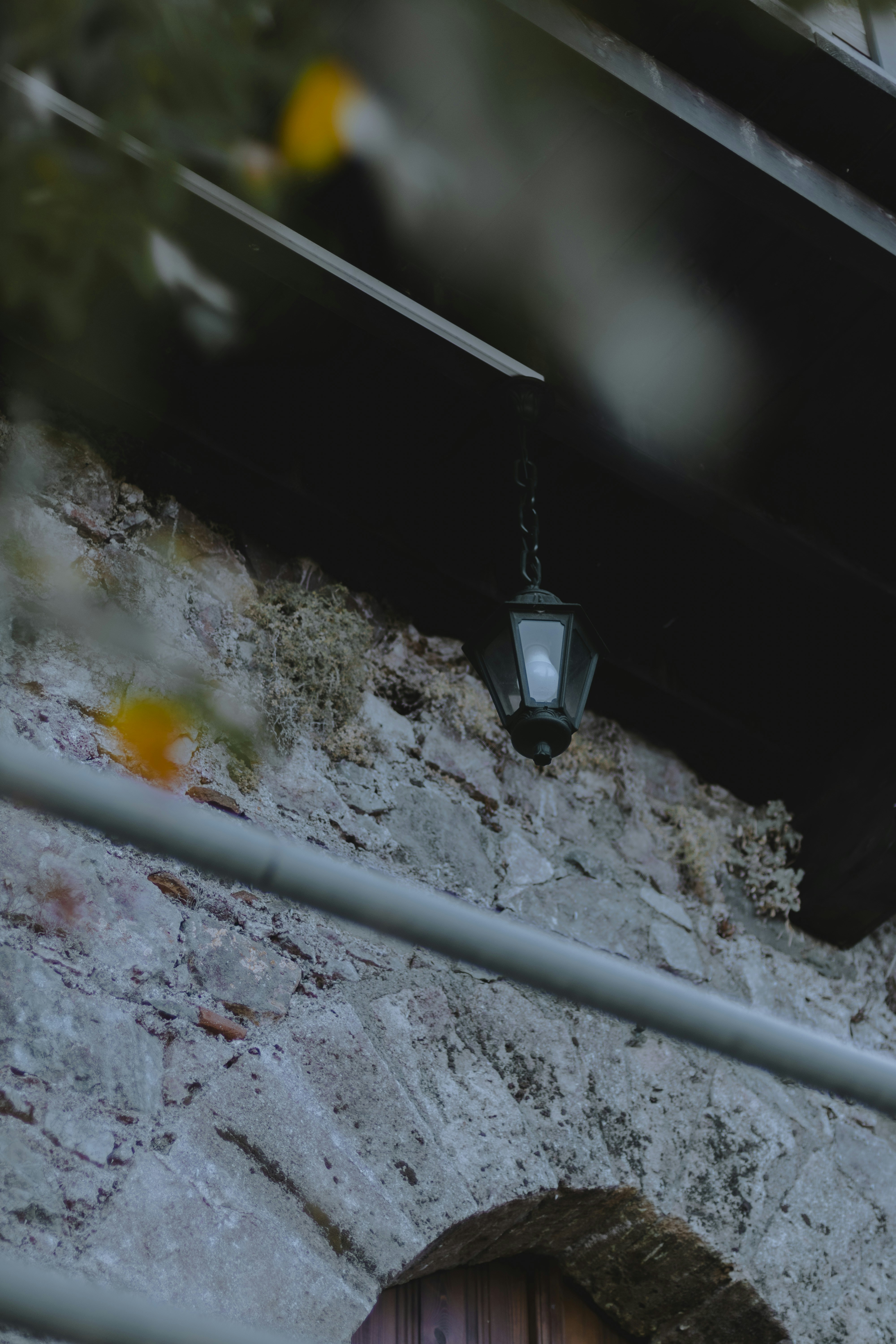 An old lantern hangs from a stone wall.