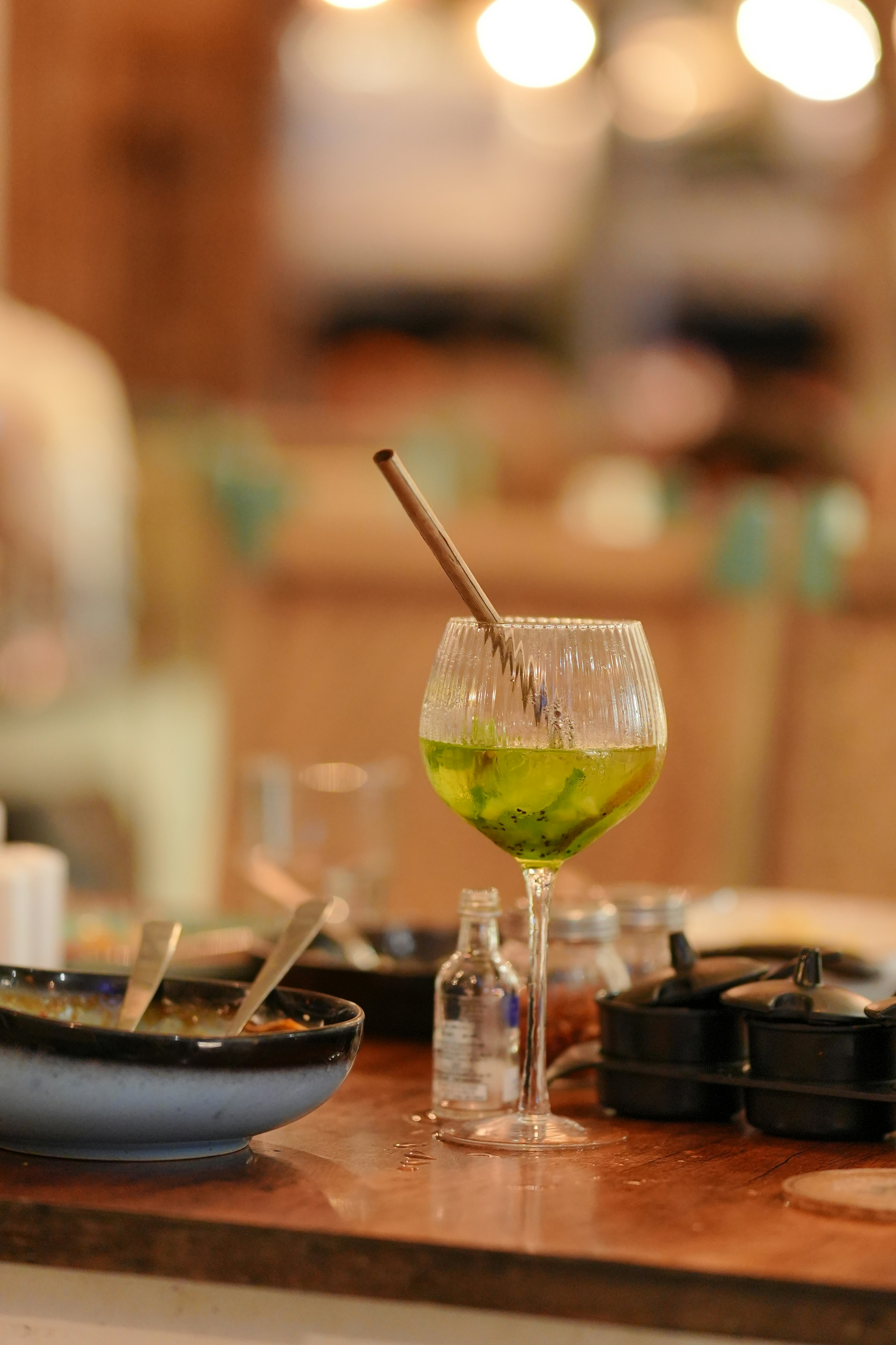 A glass of green liquid with a straw.