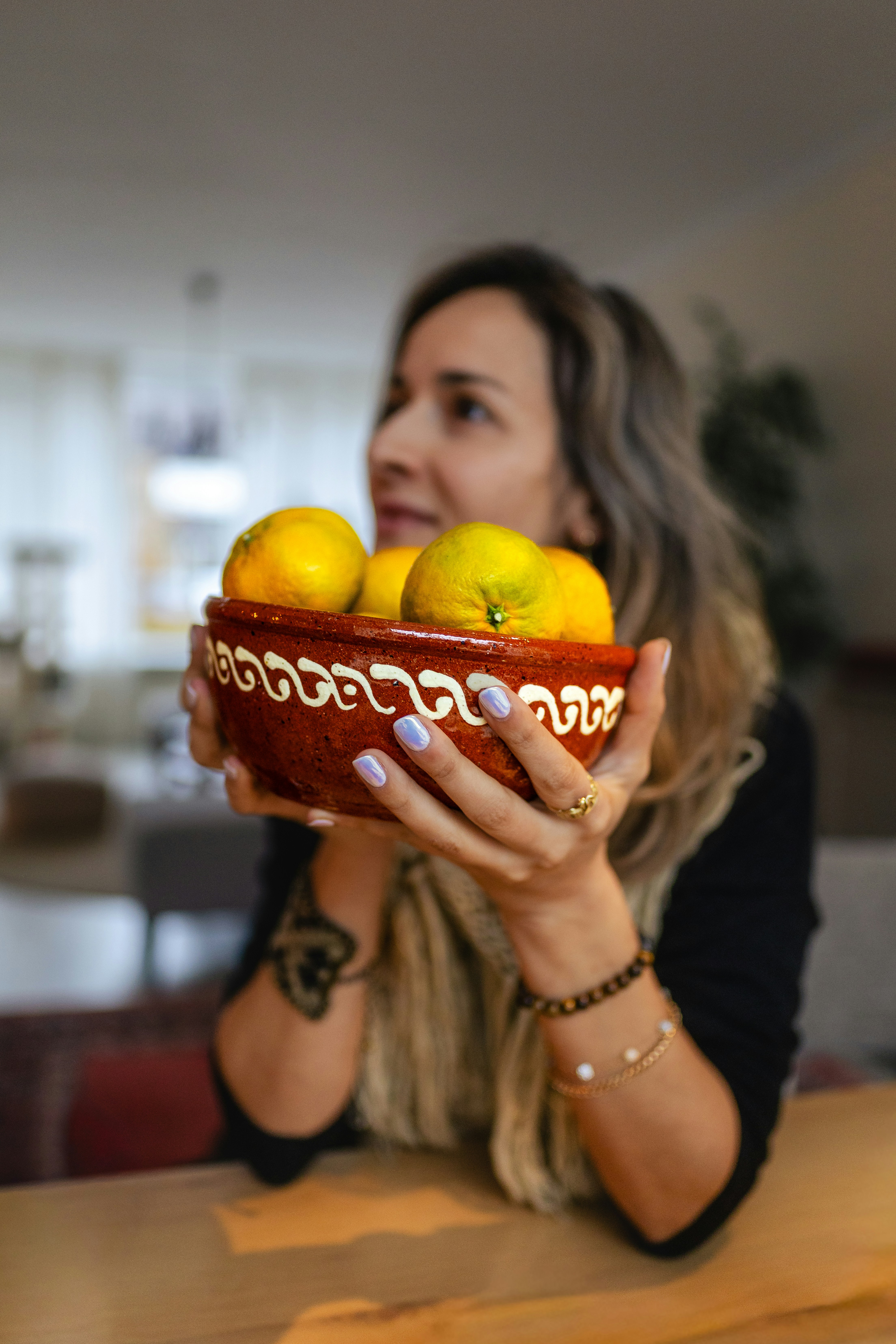 Woman holding a bowl of tangerines indoors