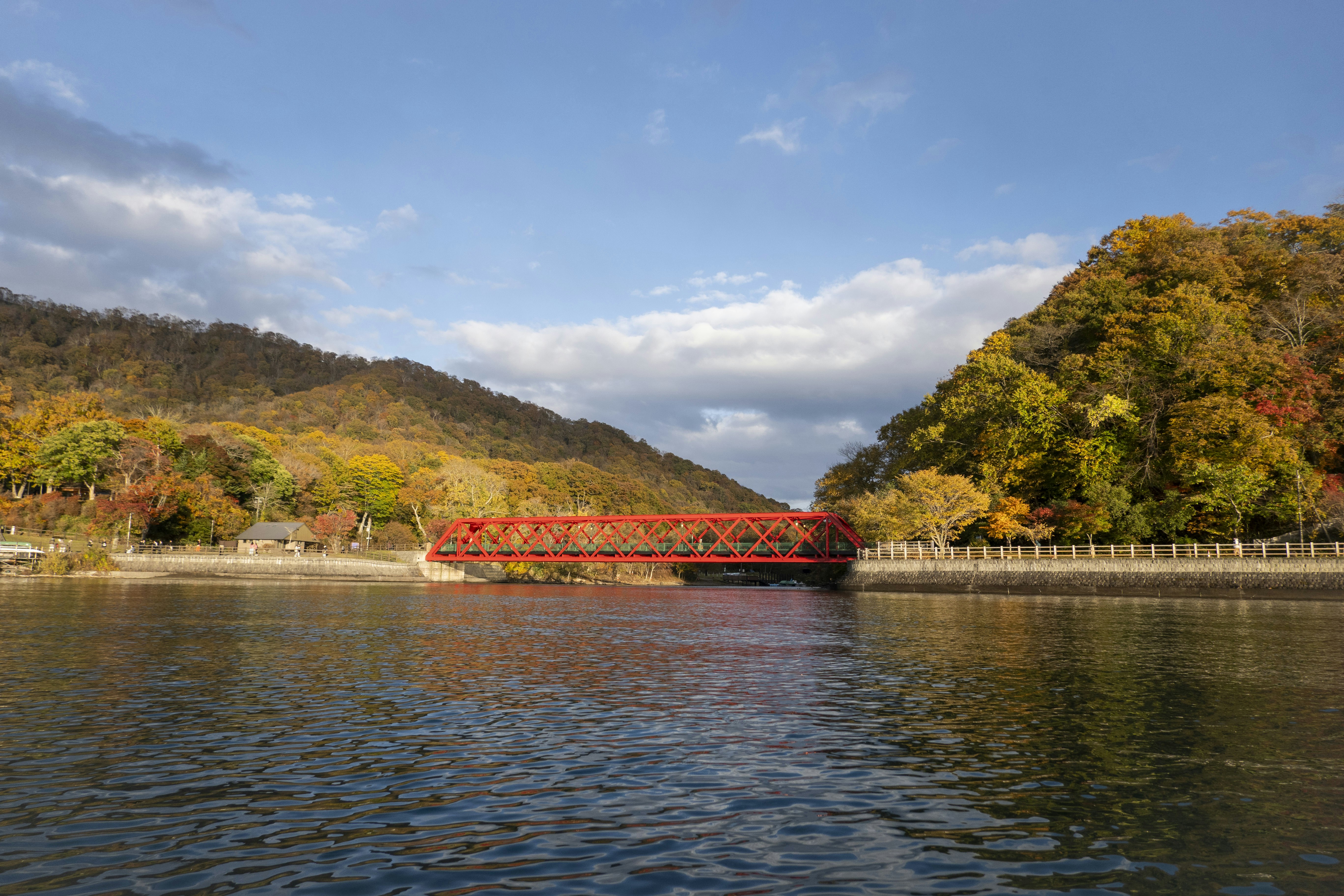 Red bridge over water with autumn foliage hills