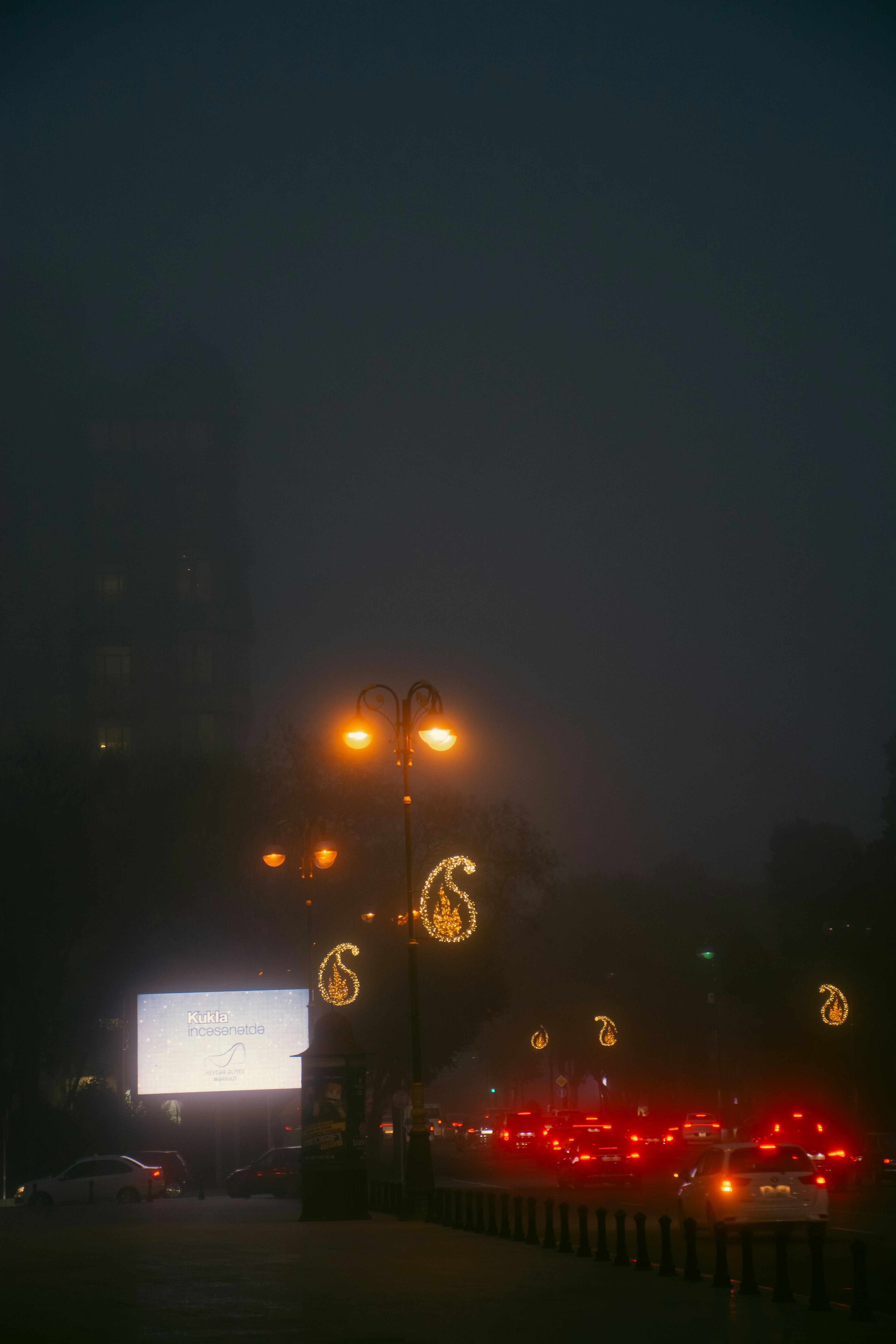 City street at night with traffic and streetlights.