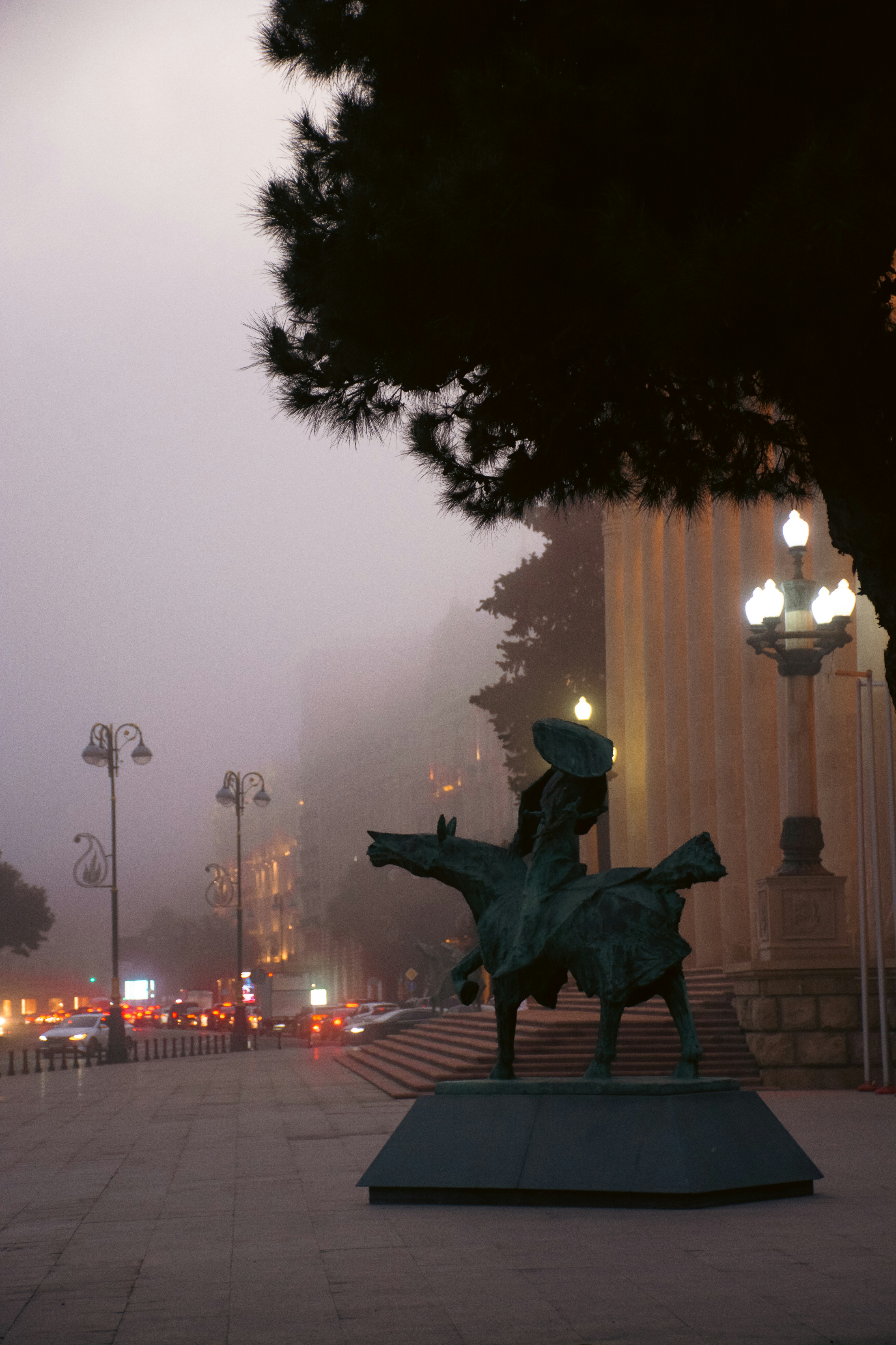 Equestrian statue in a foggy city street at dusk