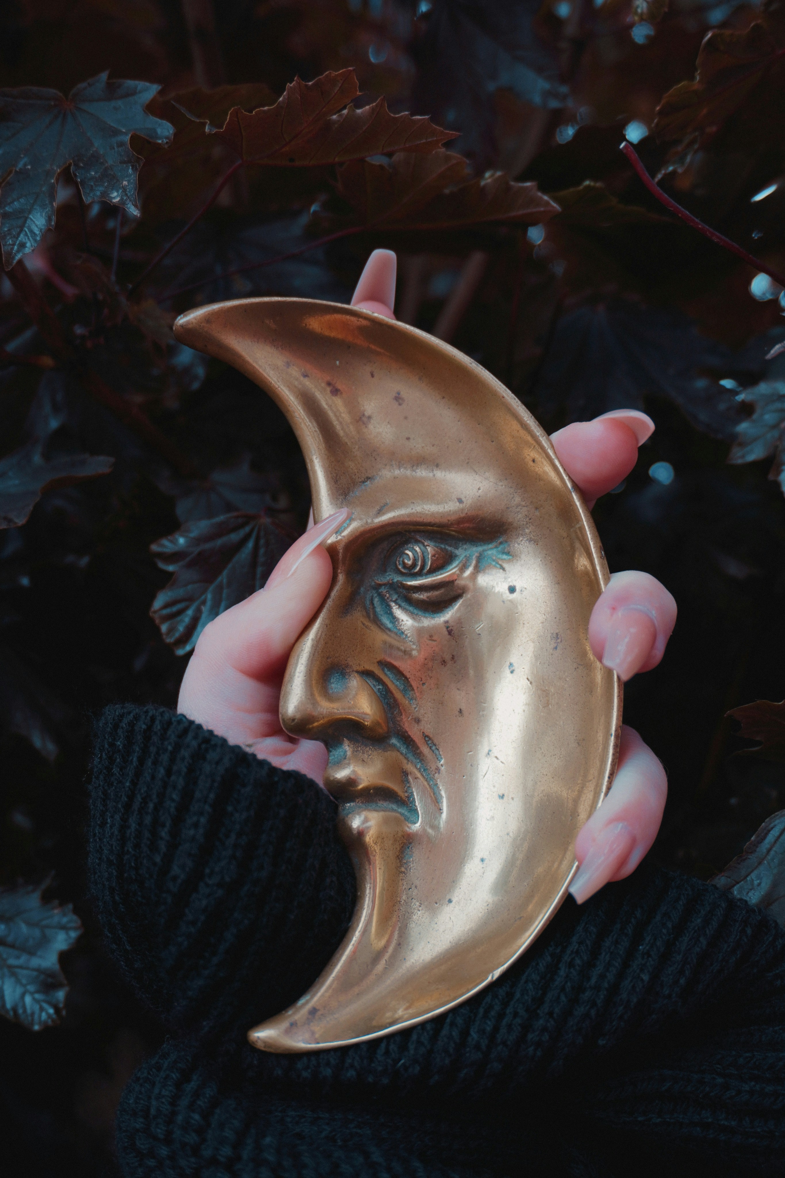 Una mano tiene una mezzaluna in ottone con una faccia