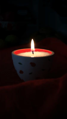 A lit candle in a decorative bowl with red accents.