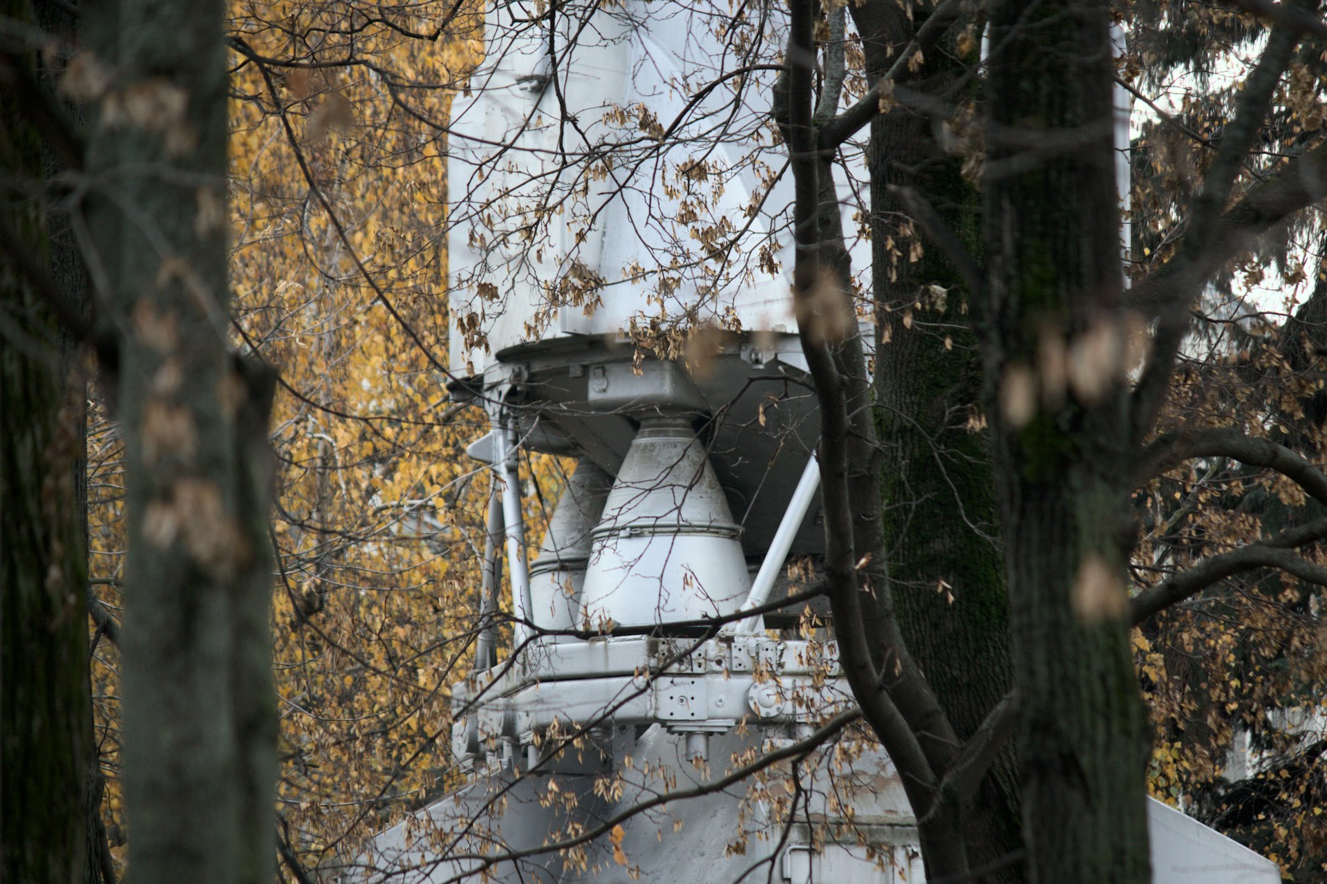 White industrial structure visible through trees