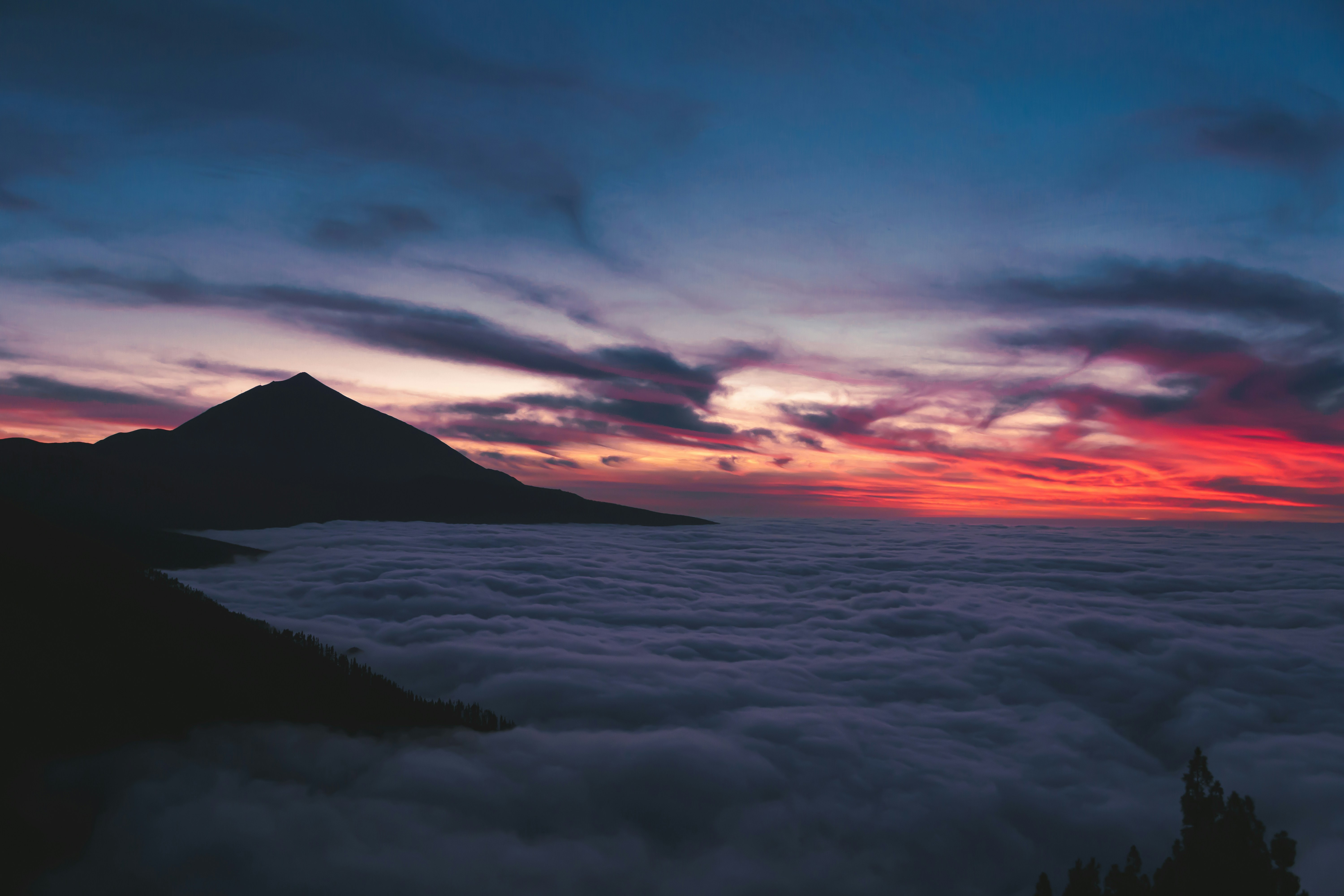 Mountain peak above clouds at vibrant sunset