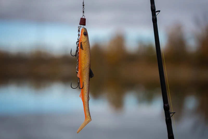 Fishing lure with treble hooks hanging from rod - fishing tackle and gear
