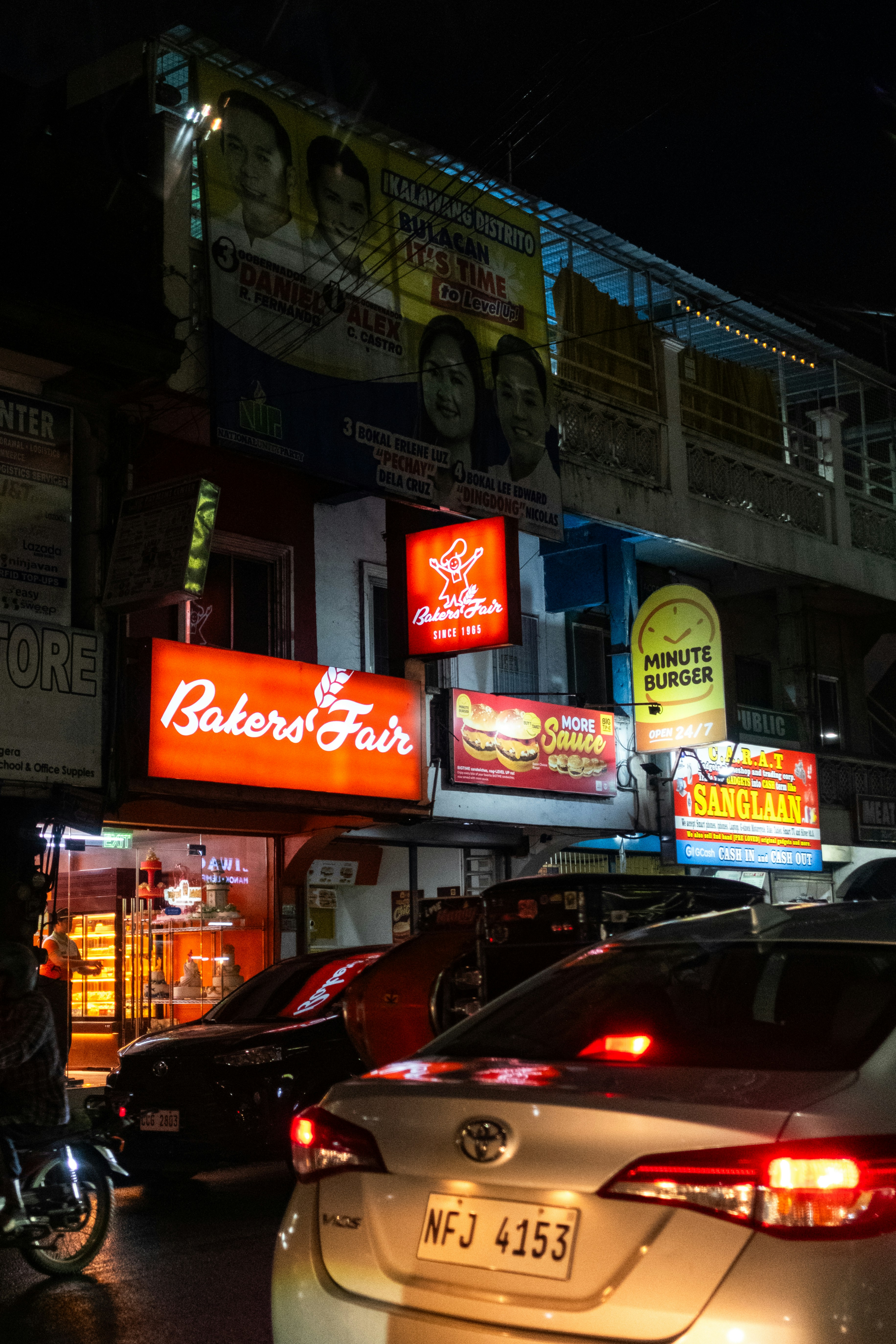 Calle de la ciudad por la noche con señales luminosas y tráfico.