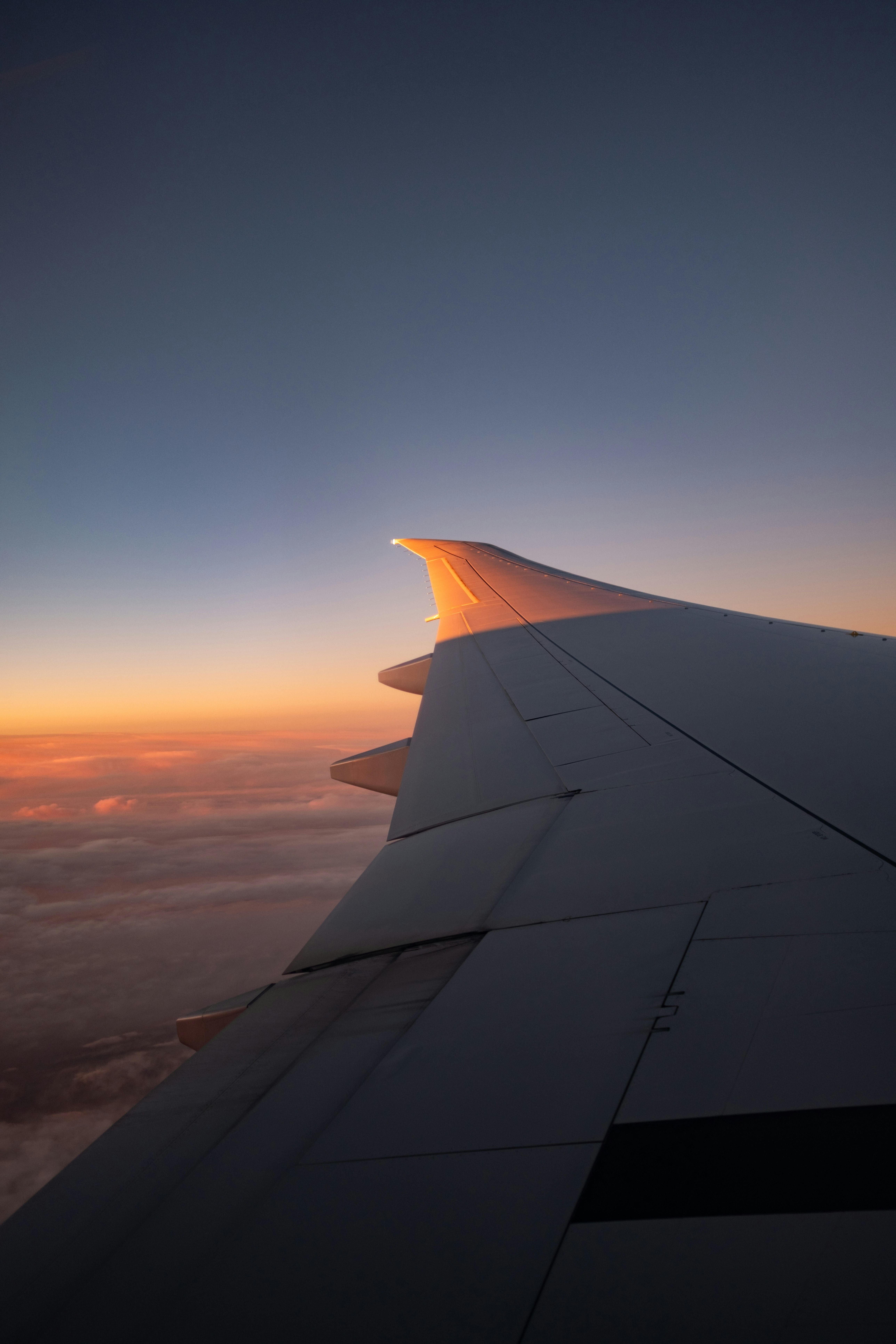 Ala de avión contra un cielo al atardecer sobre las nubes