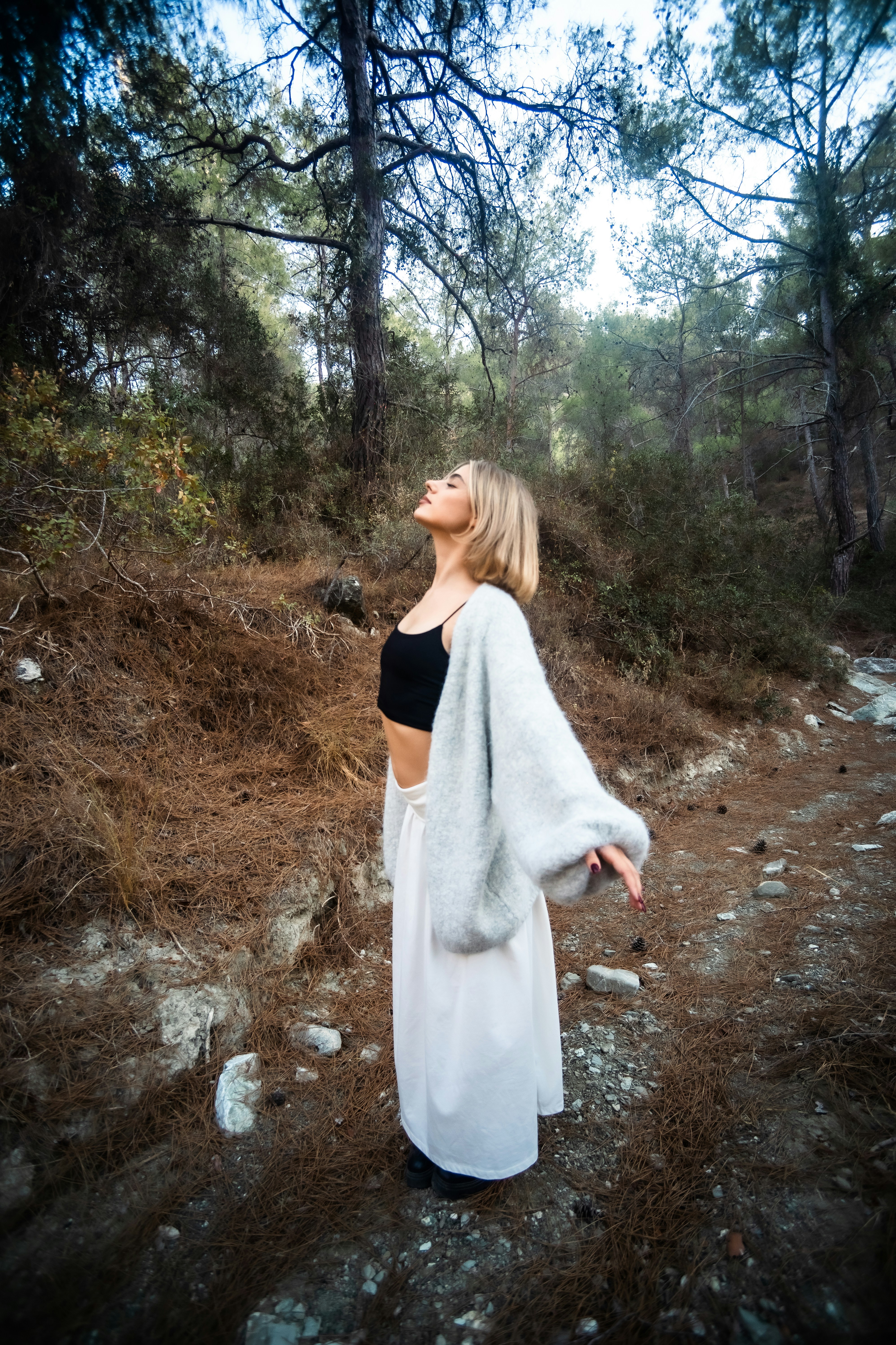 Woman standing outdoors with arms open in a calm forest setting