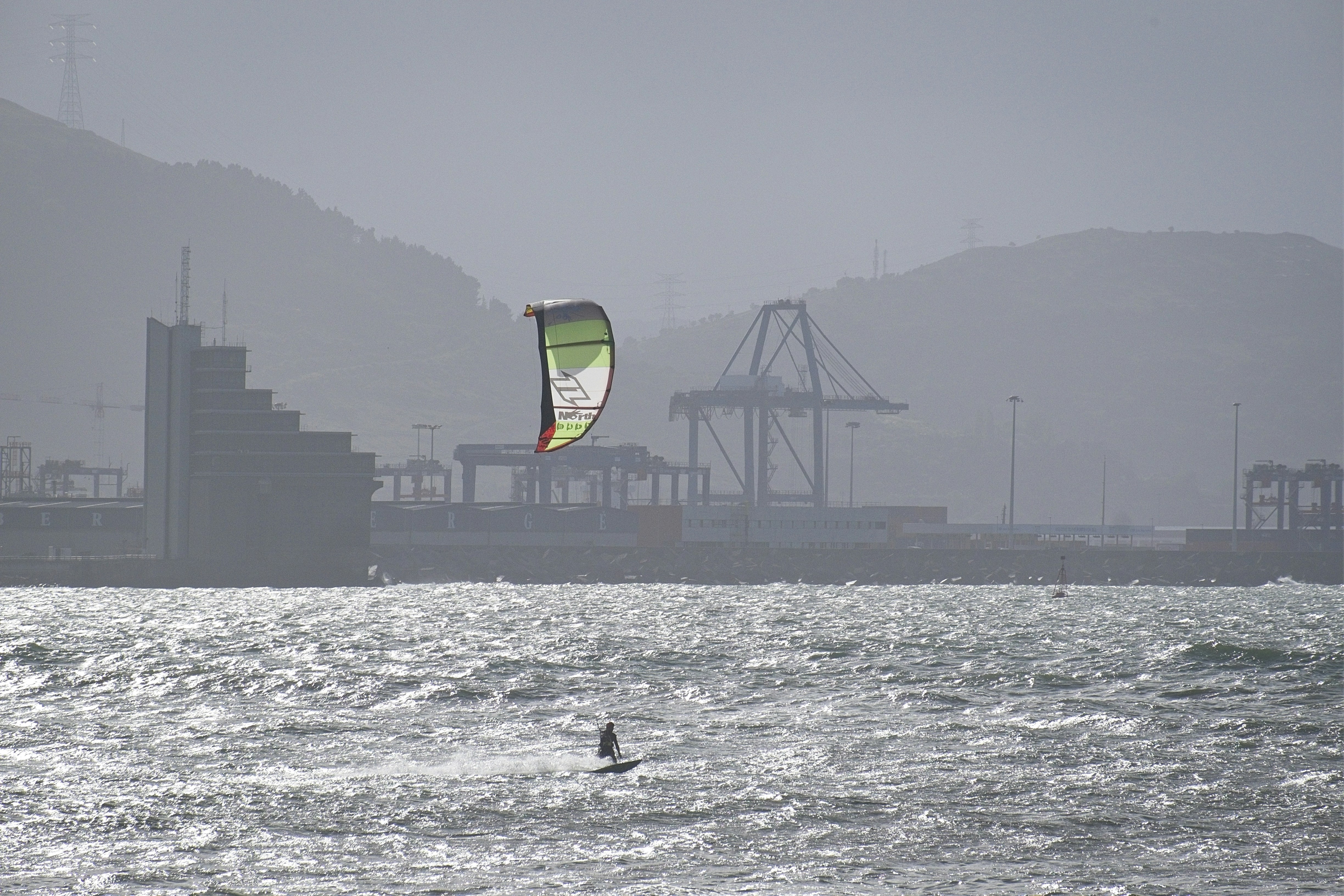 Kitesurfer on choppy water with industrial background