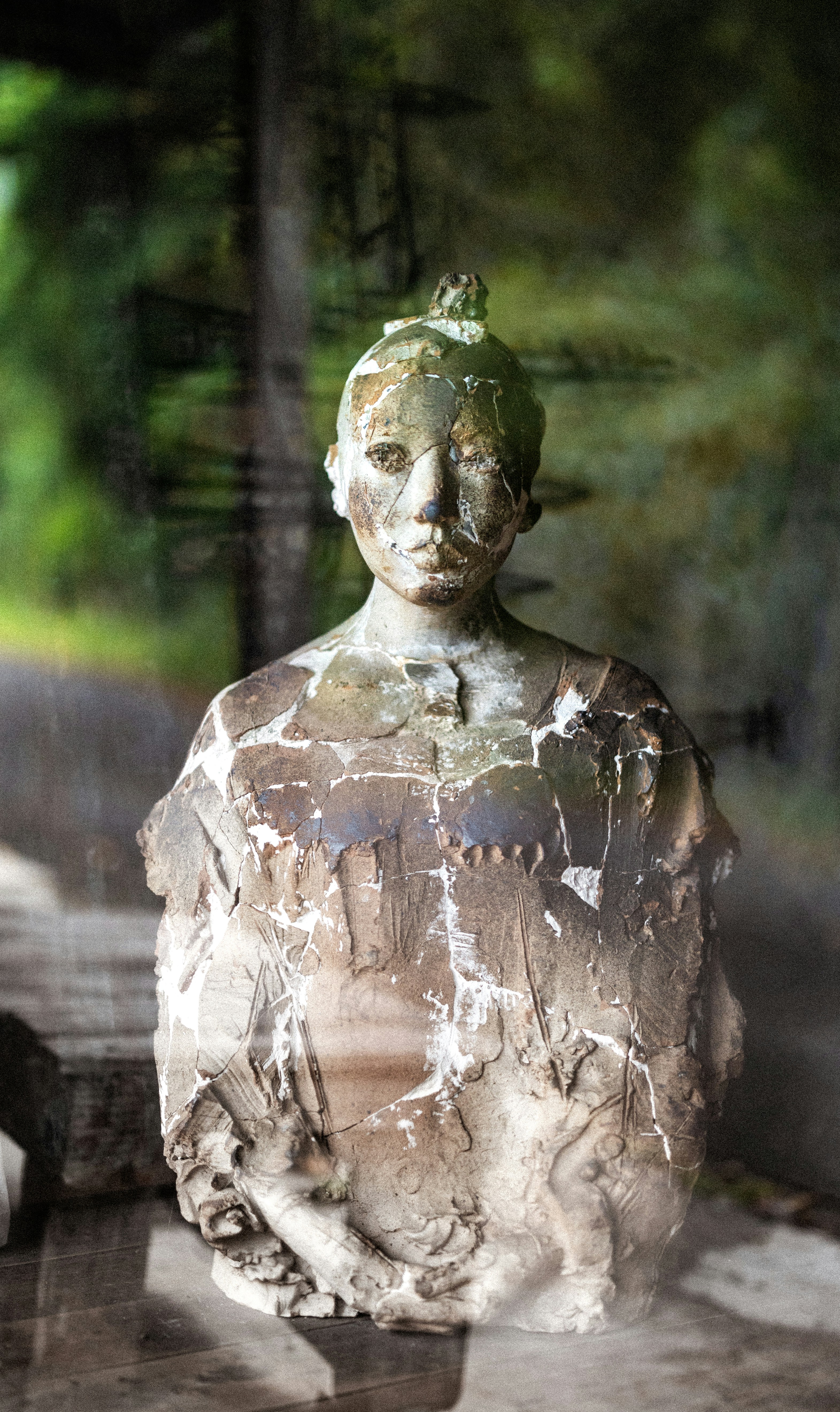 A weathered bust of a person in an outdoor setting.