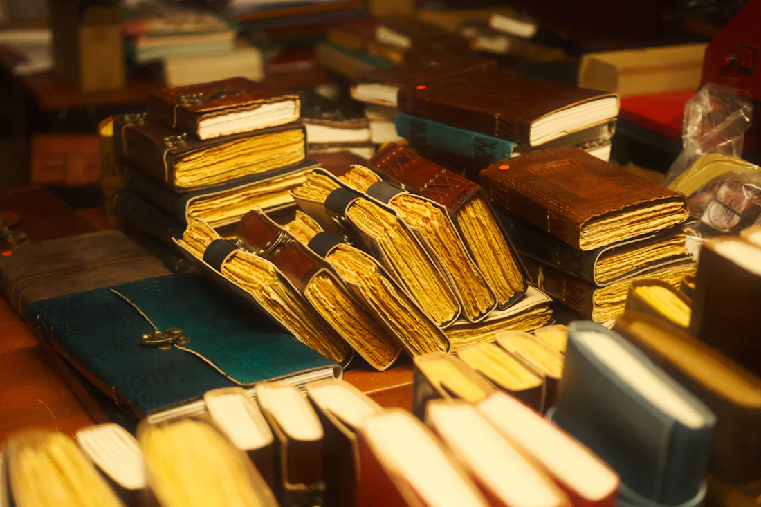 Ledergebundene Bücher mit gealterten Seiten, dicht gestapelt in goldwarmem Licht