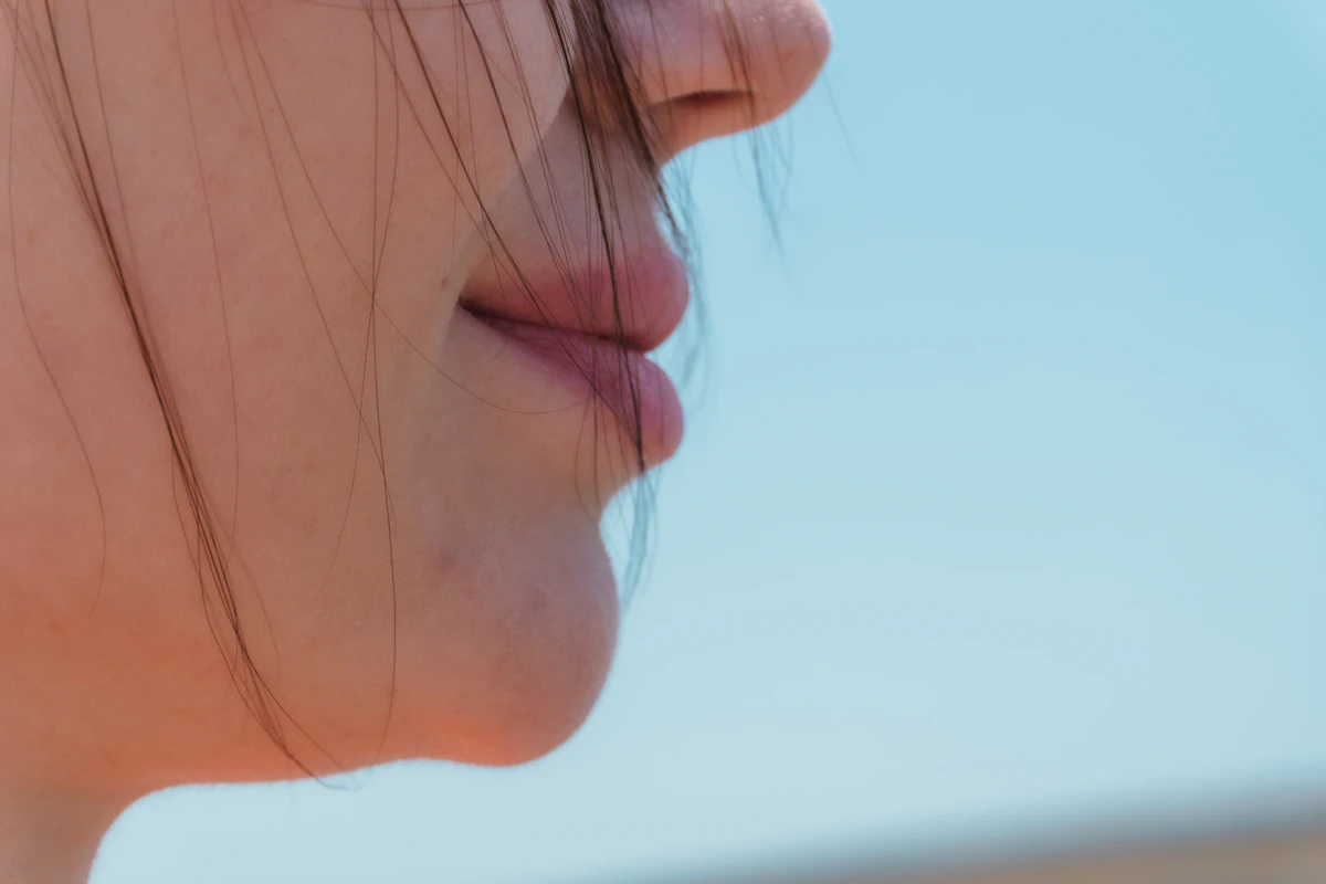 Profil eines Mundes vor blauem Himmel als Symbol für frischen Atem