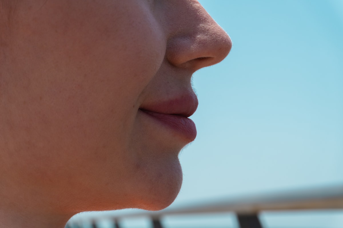 A close-up profile of a person's mouth and chin showing skin texture