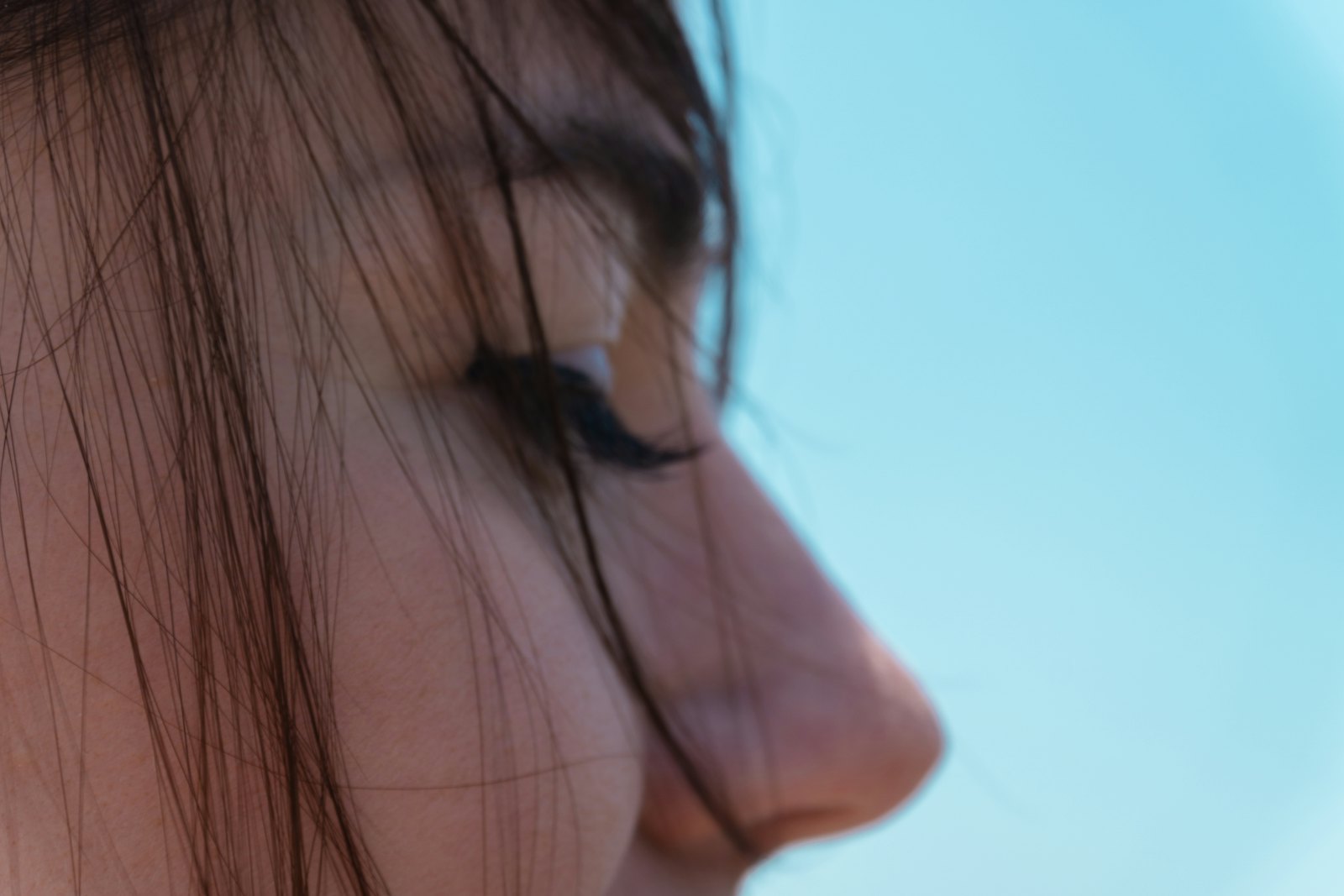 Profile view of woman outdoors highlighting refined rhinoplasty results