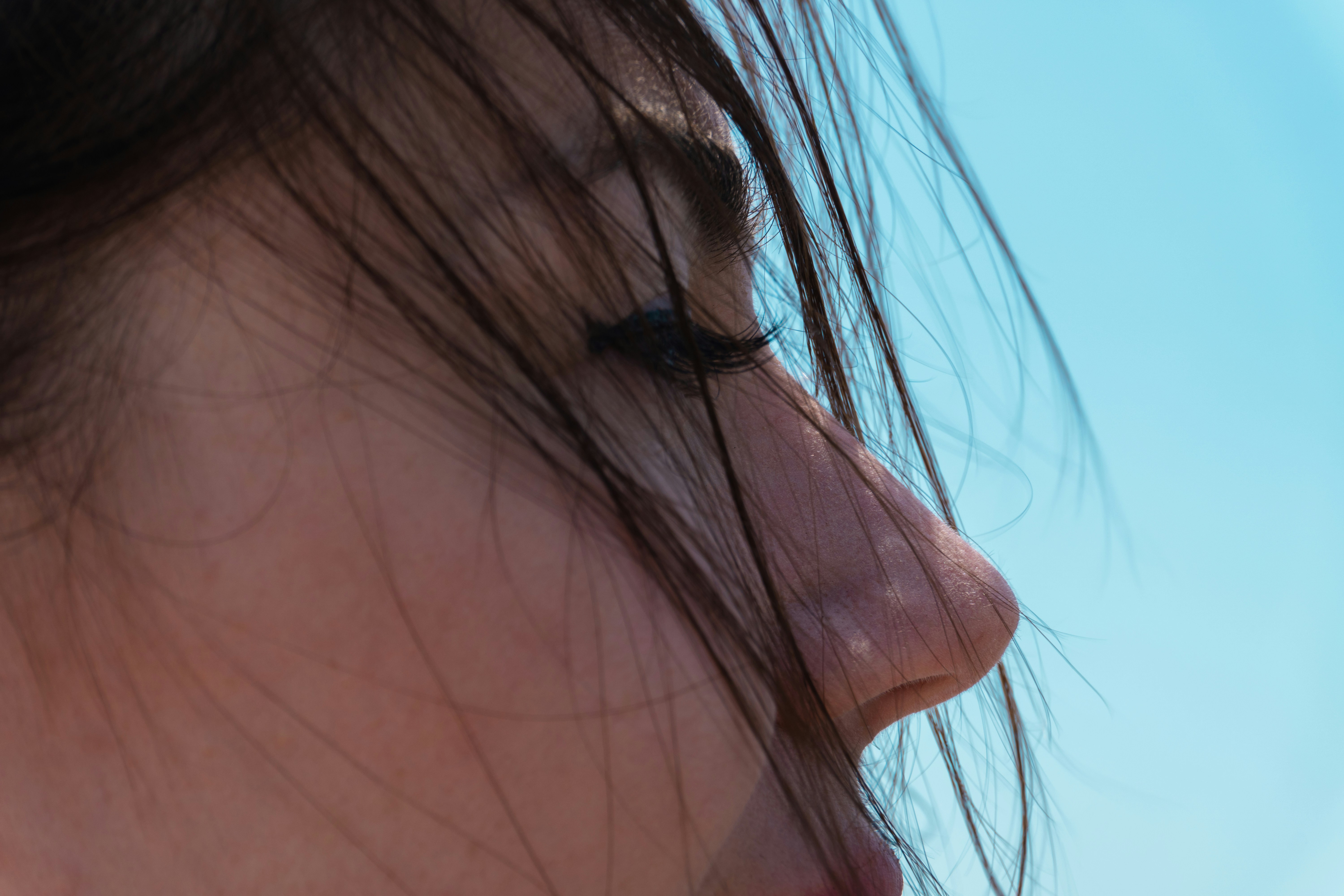 Close-up profile of a young woman against blue sky