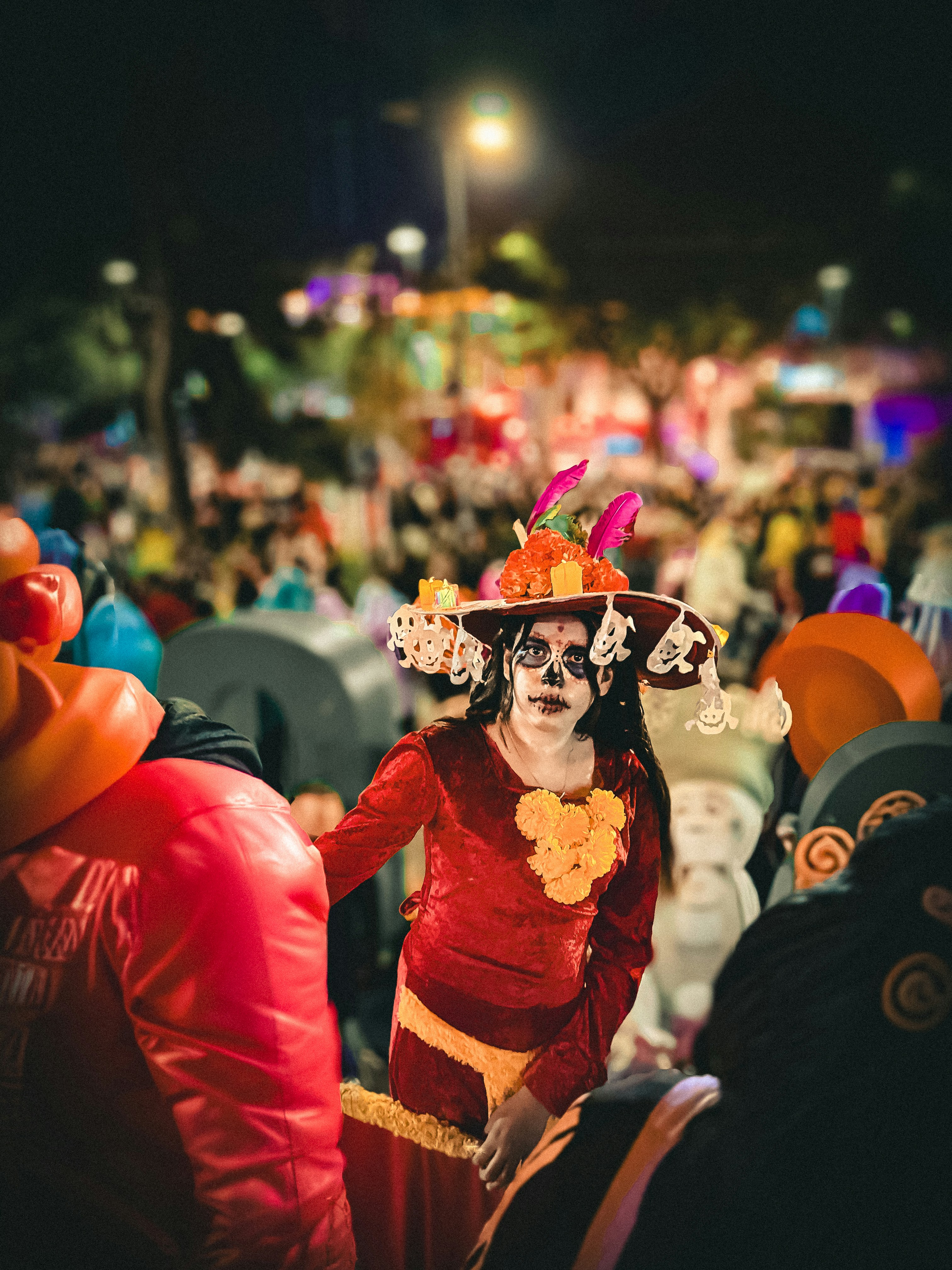 Wanita dengan riasan kerangka dan pakaian meriah di malam hari