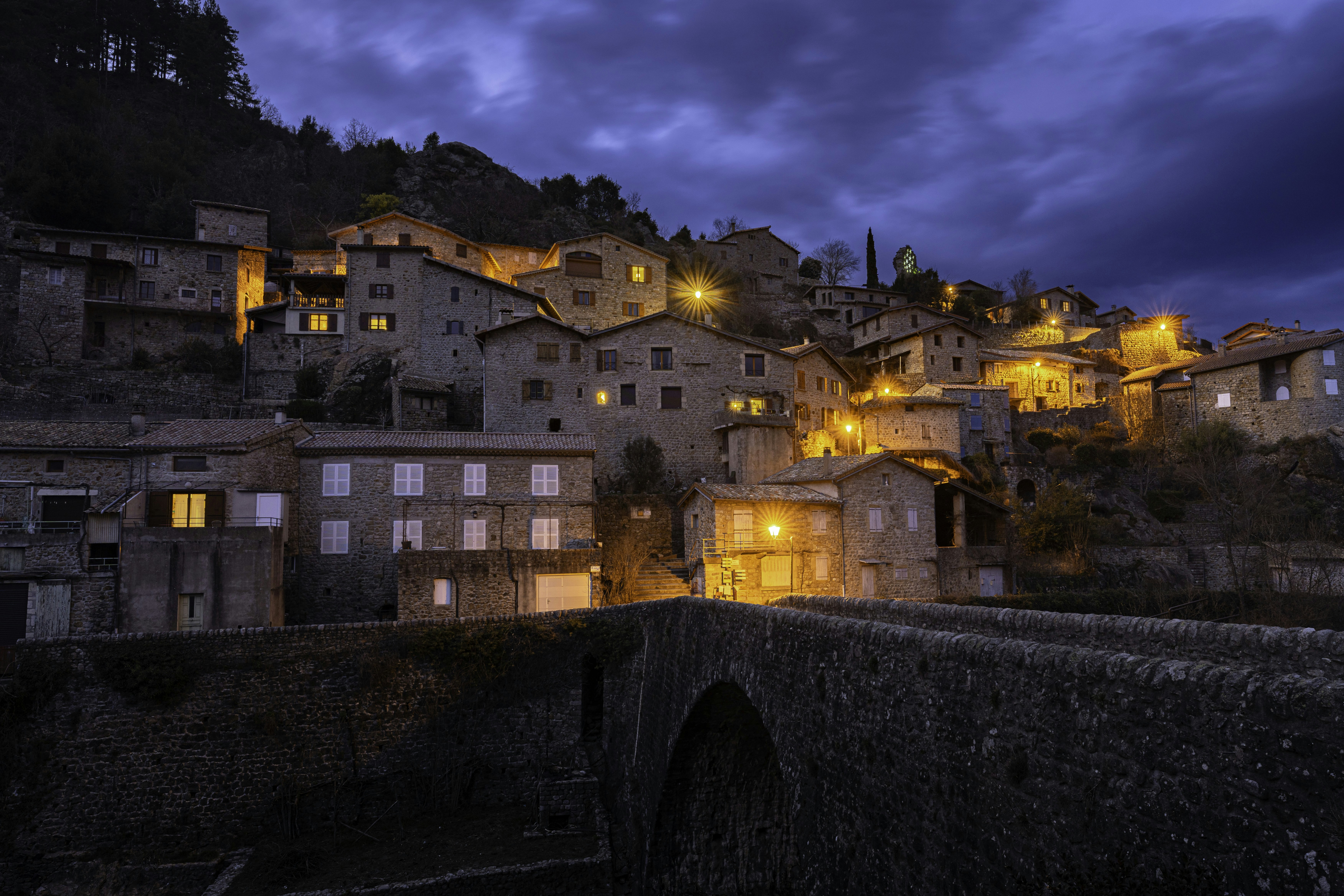 Village nestled on hillside at dusk with bridge
