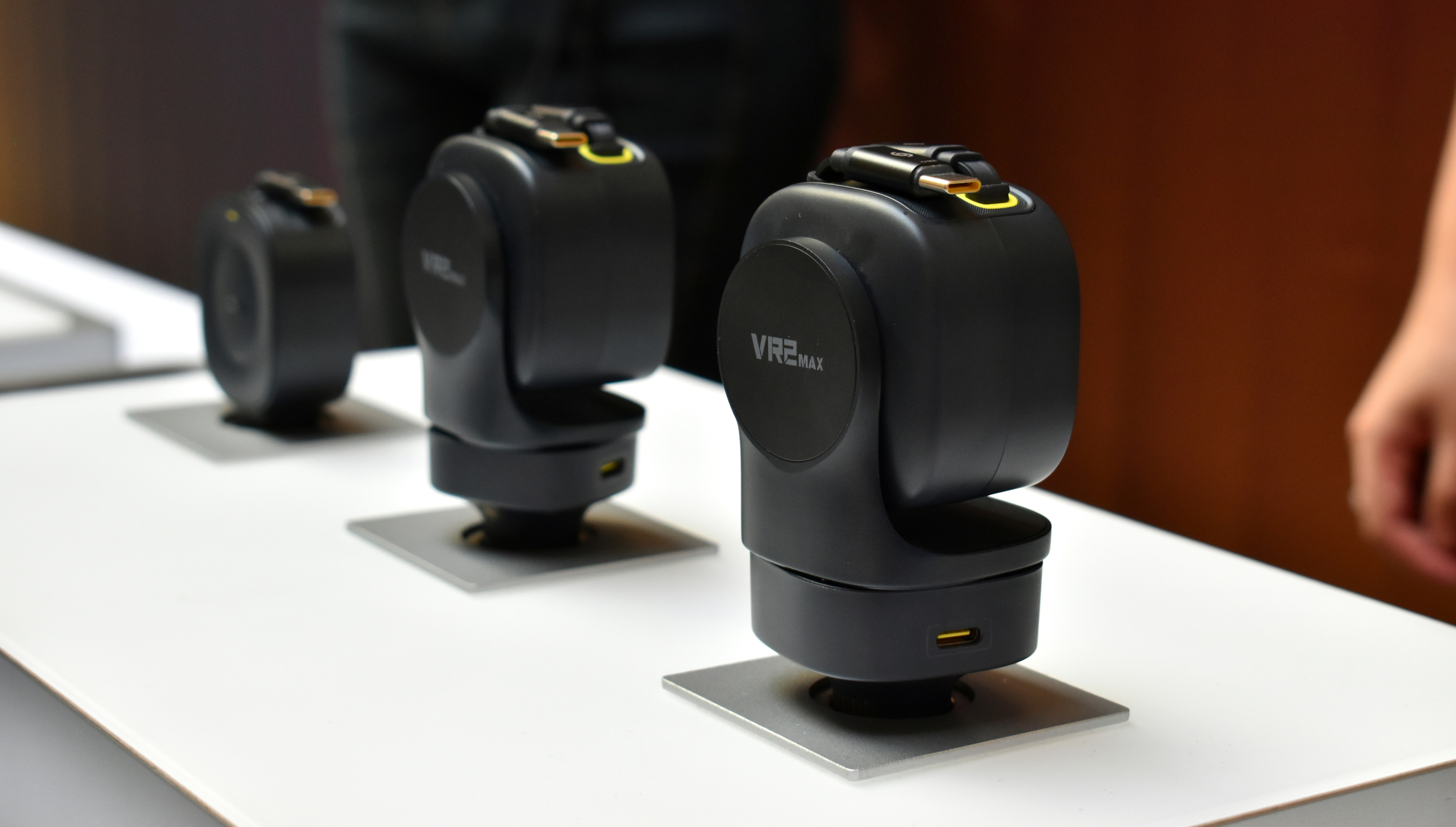 Three black camera stabilizers on a white surface.