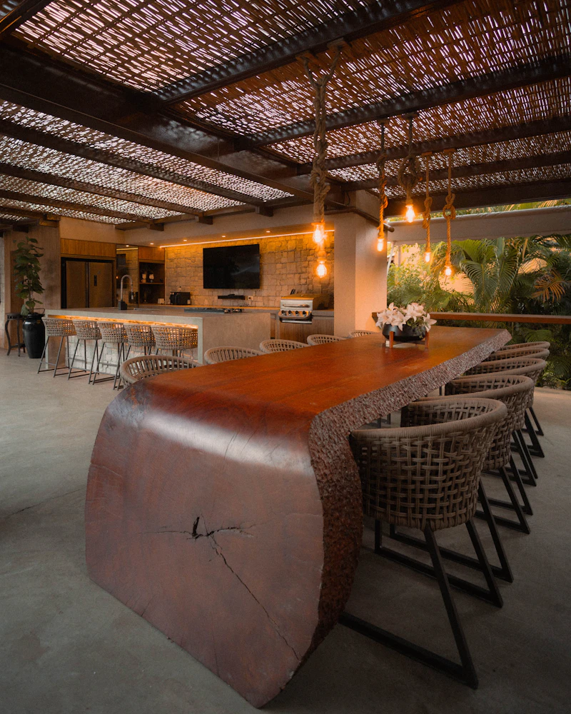 Tropical outdoor dining pavilion with live-edge wood table and warm lighting