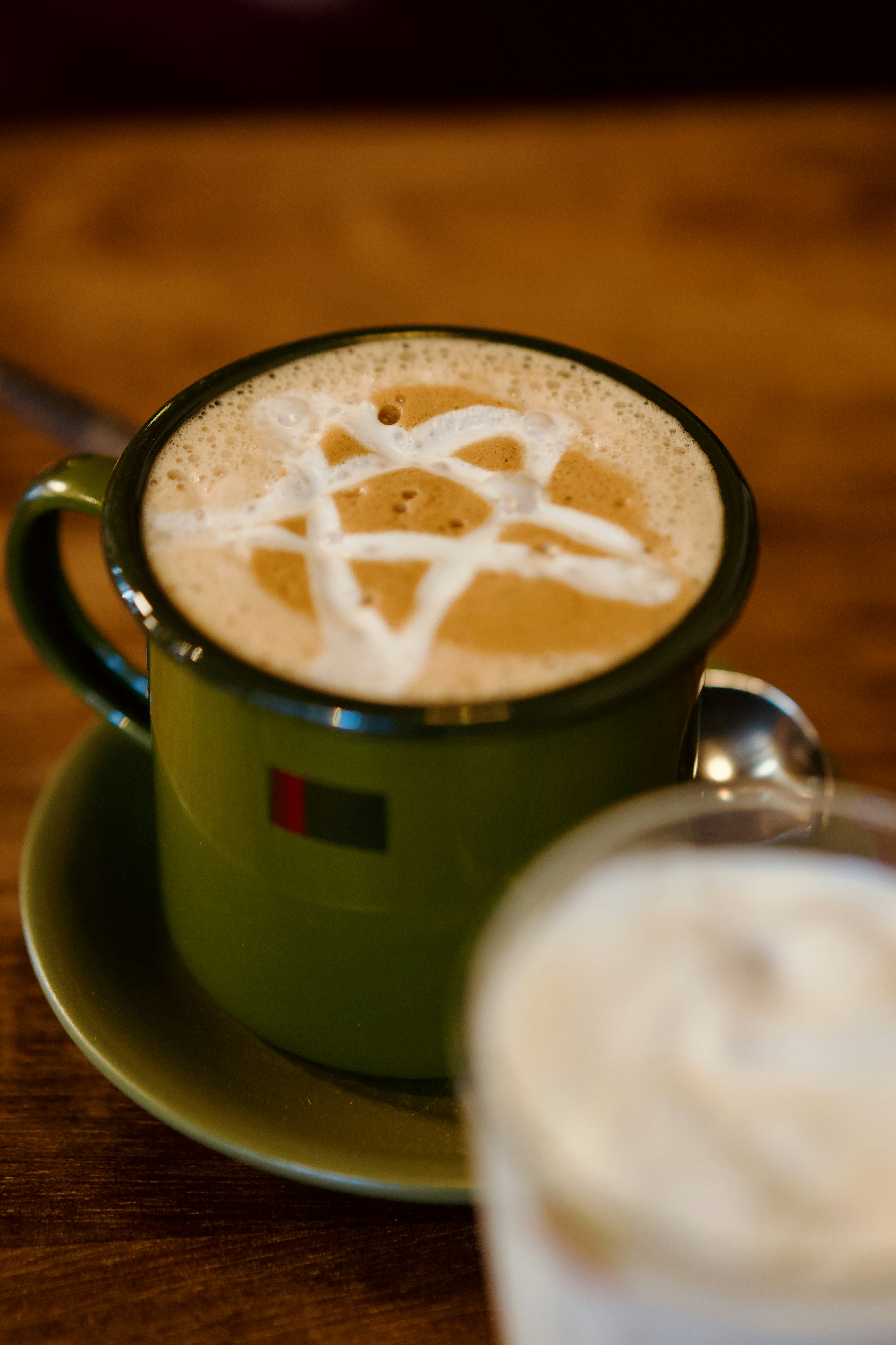 A green mug filled with a creamy latte