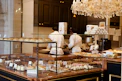 Pastry display case with chefs preparing food in background.