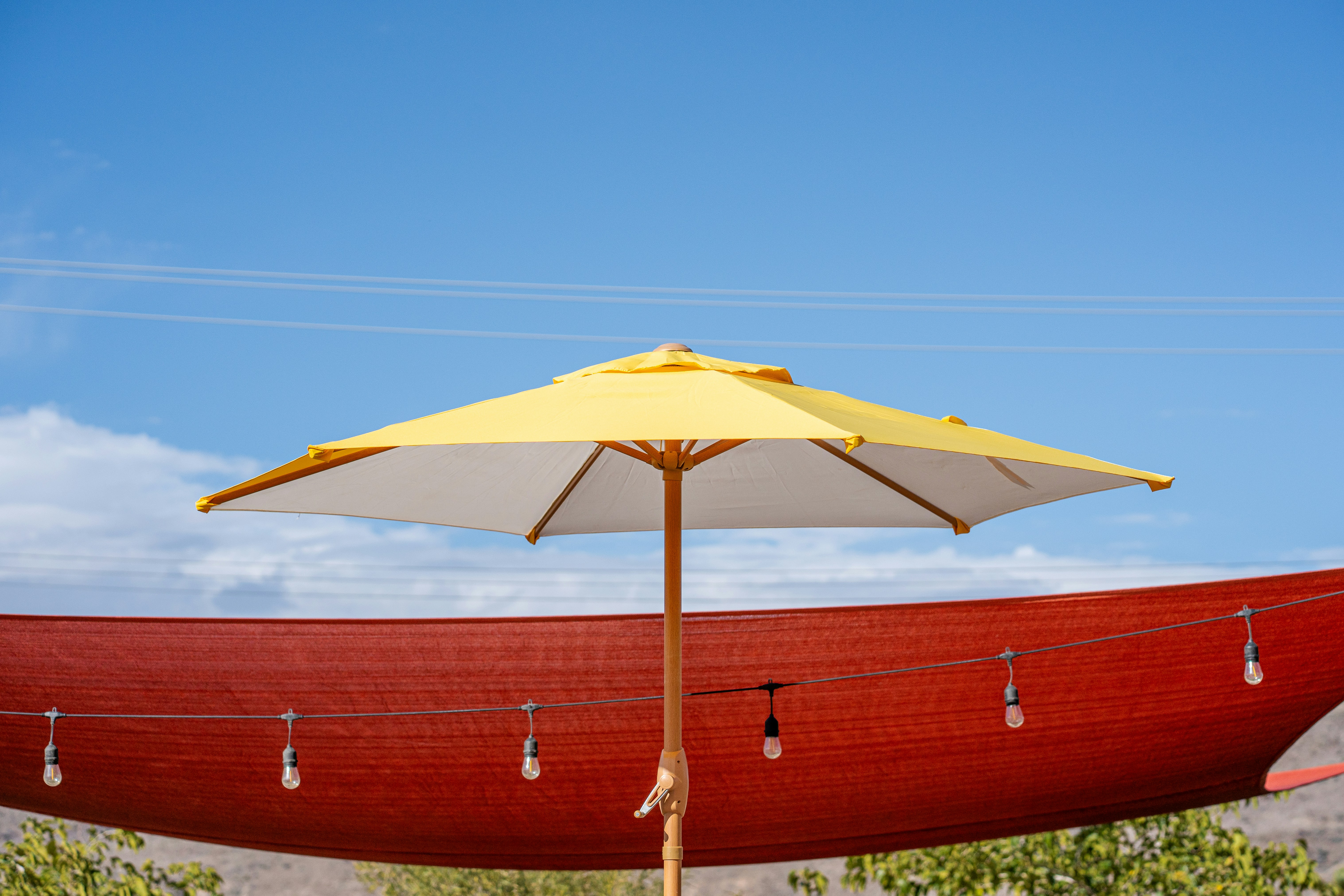 Yellow umbrella against red shade cloth and sky
