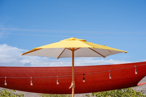 Yellow umbrella against red shade cloth and sky