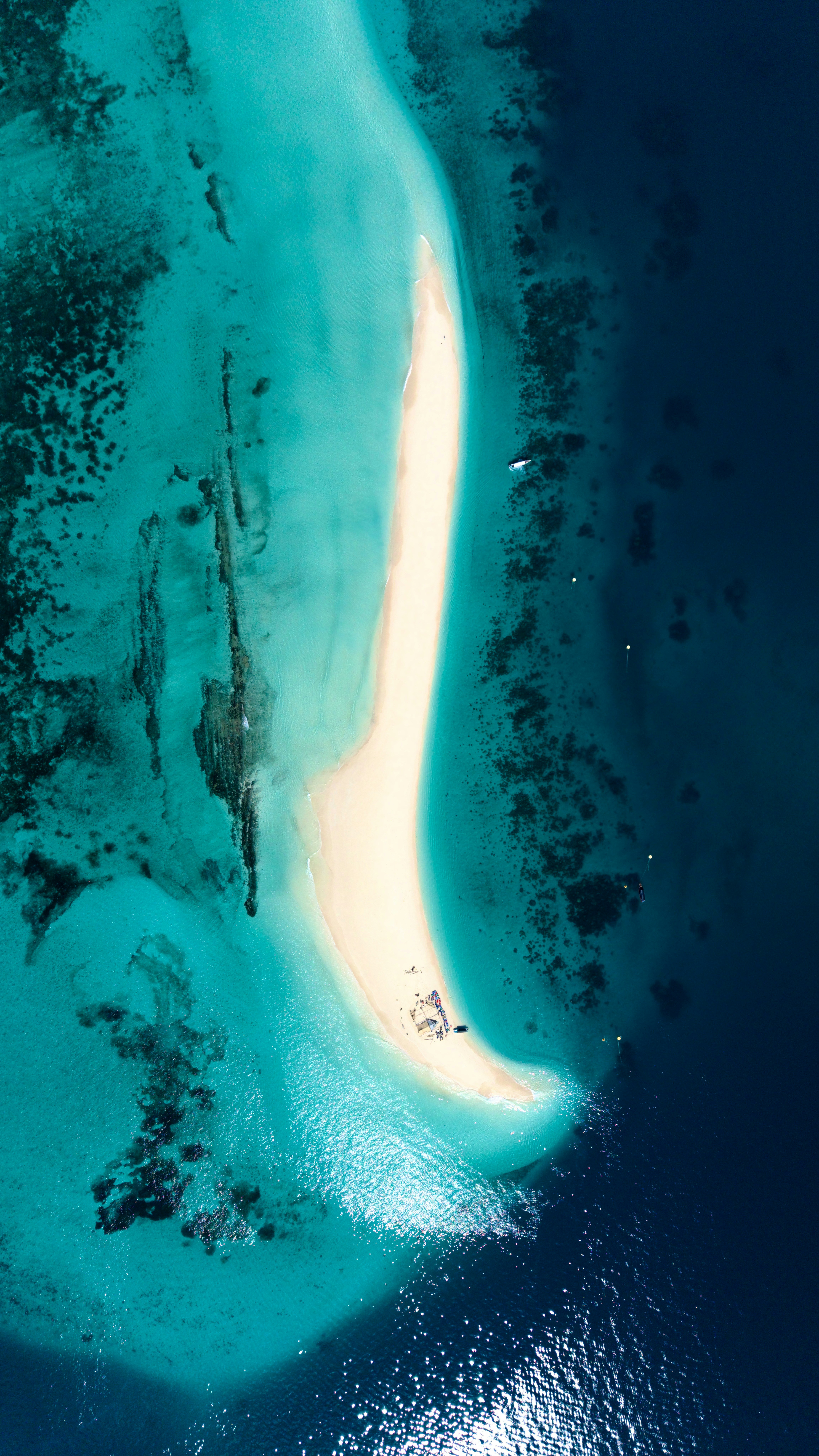 Aerial view of a sandbar surrounded by turquoise water.