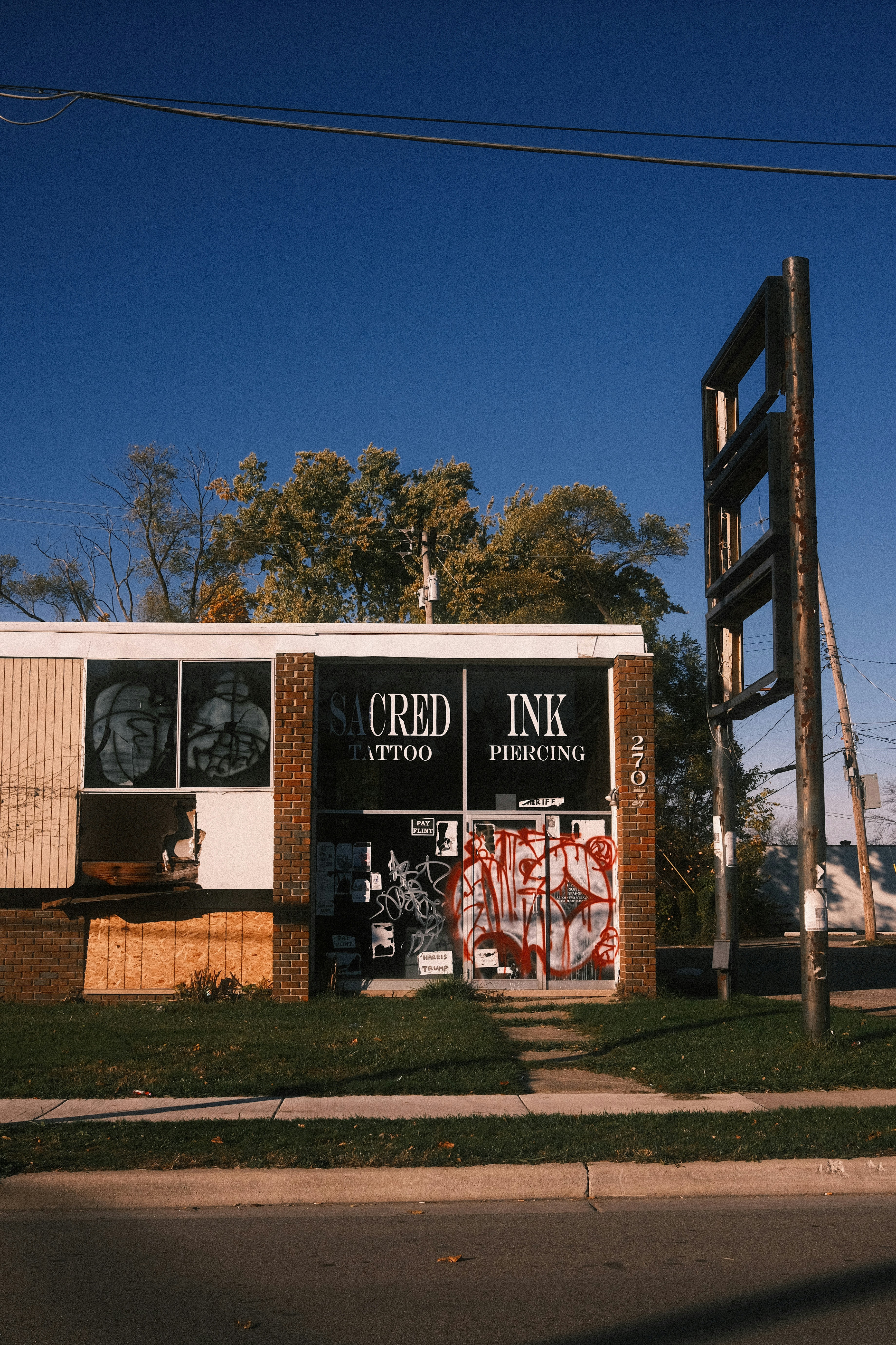 Tattoo and piercing shop with graffiti on windows.