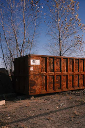 Rusty industrial dumpster in an outdoor lot.