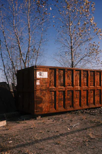 Rusty industrial dumpster in an outdoor lot.