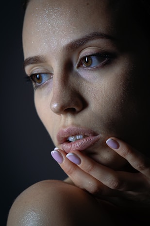 A woman's face with hand touching her chin