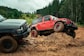 Two off-road vehicles navigating a muddy trail.