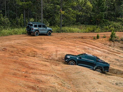 Two suvs driving on a dirt track