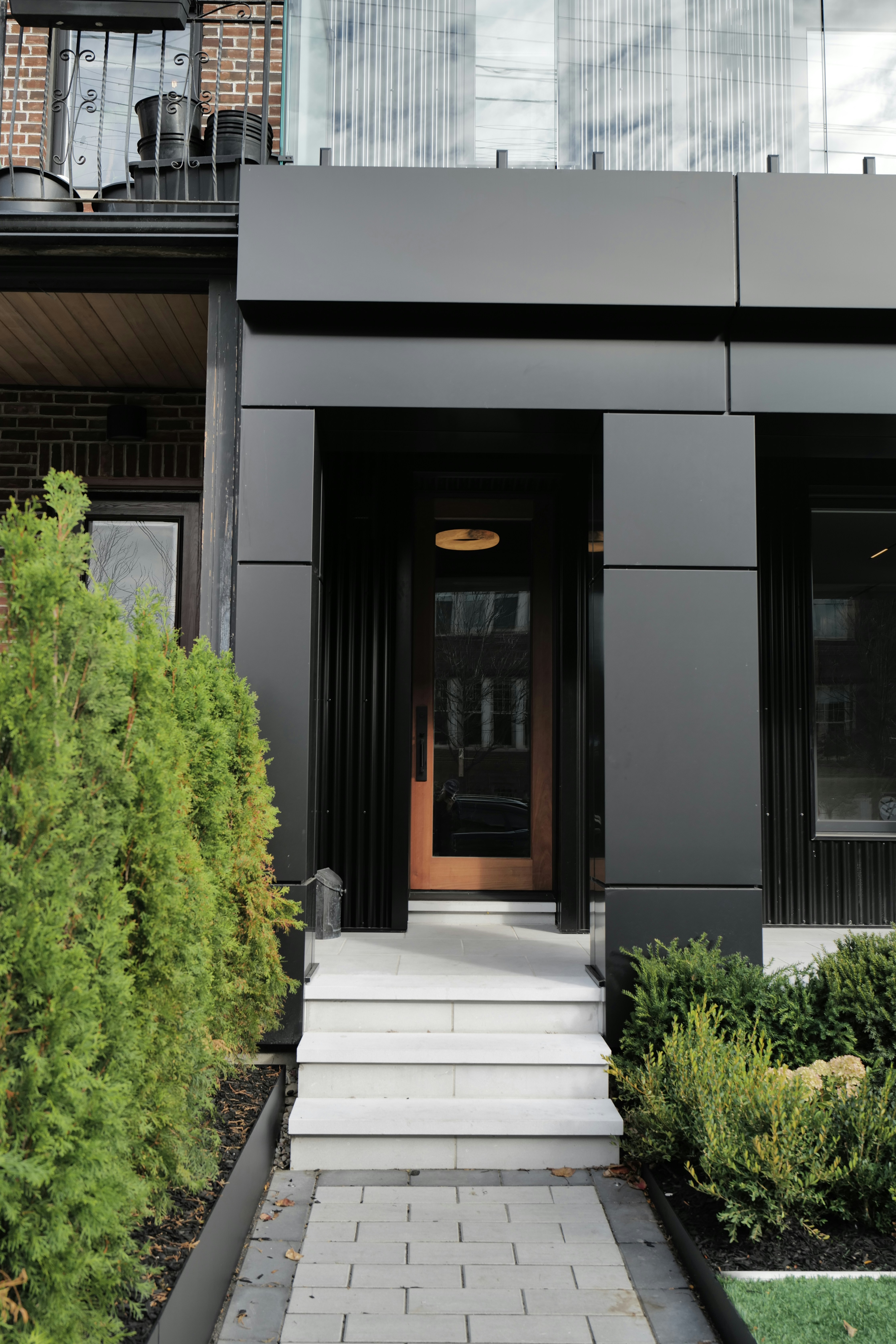 Modern black entrance with white stairs and greenery