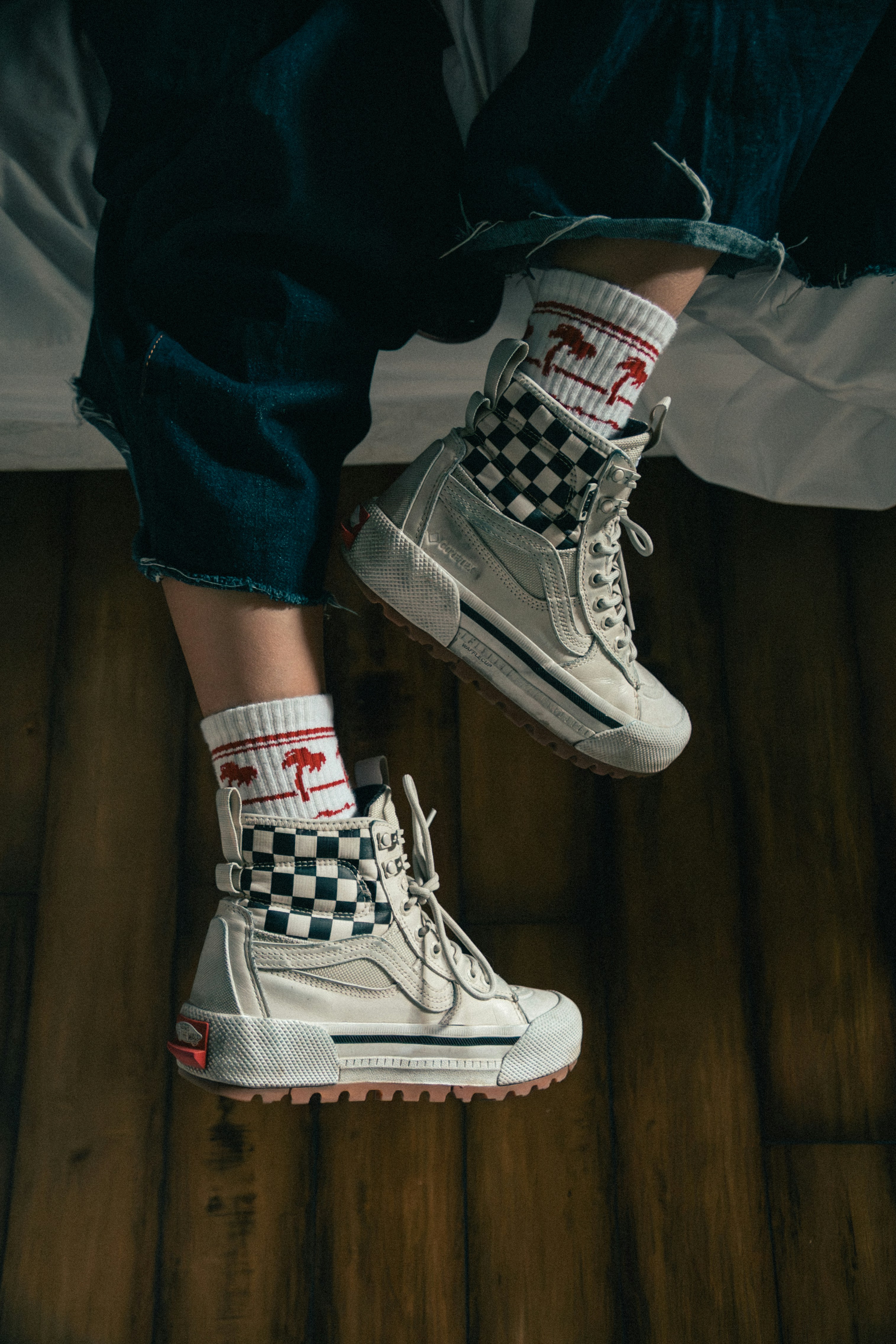 Person wearing white high-top sneakers and patterned socks