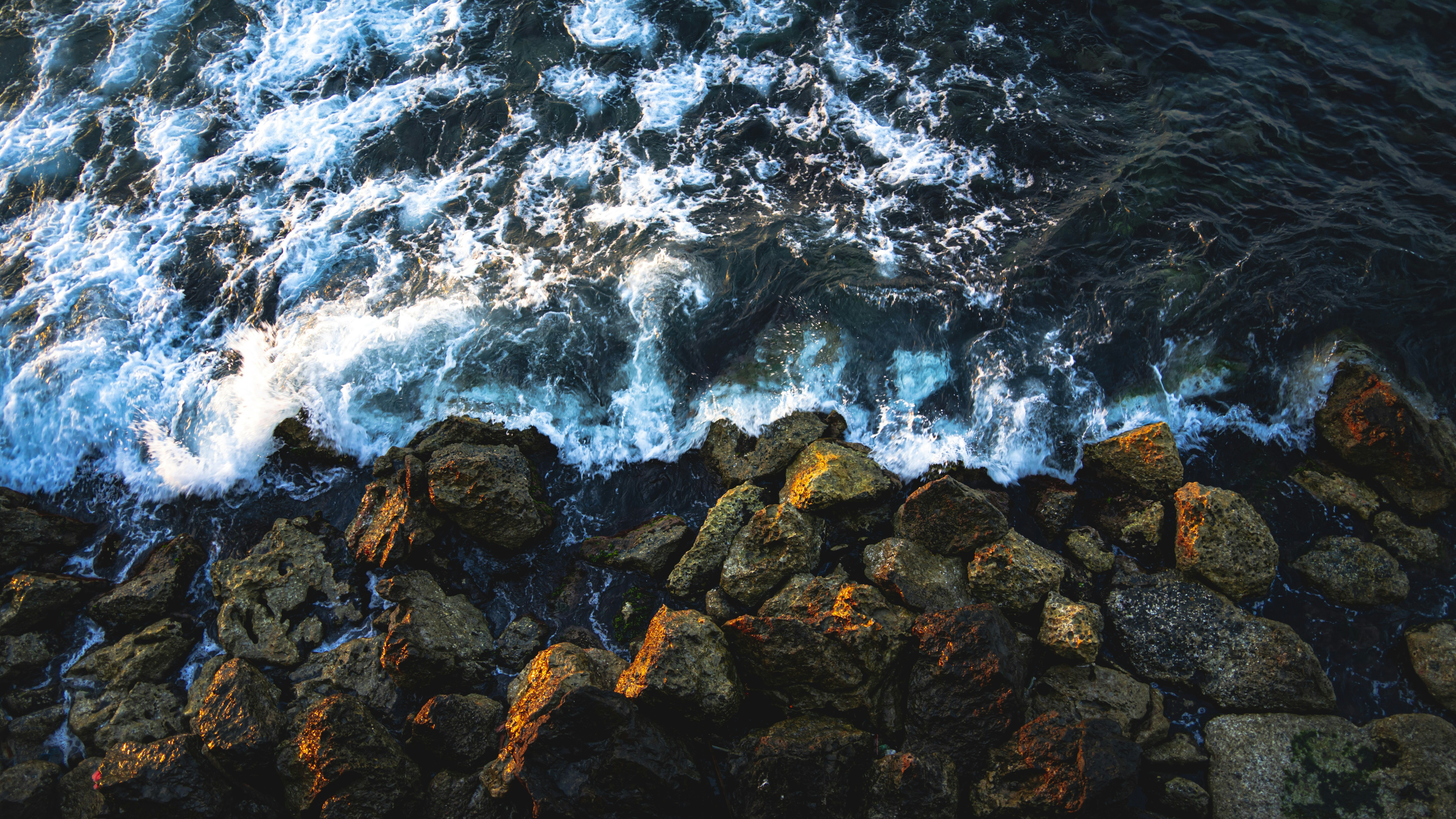 Waves crashing on a rocky shore at sunset.