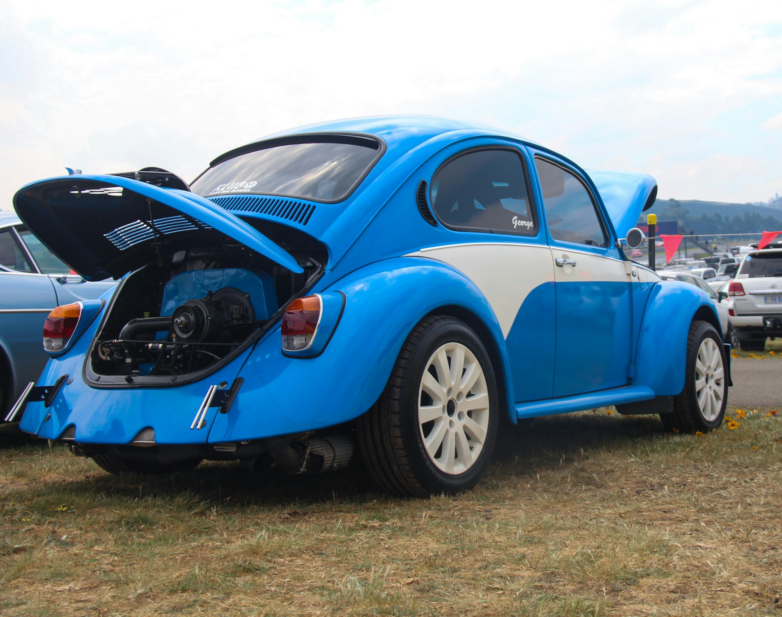 Blue and white volkswagen beetle with engine exposed