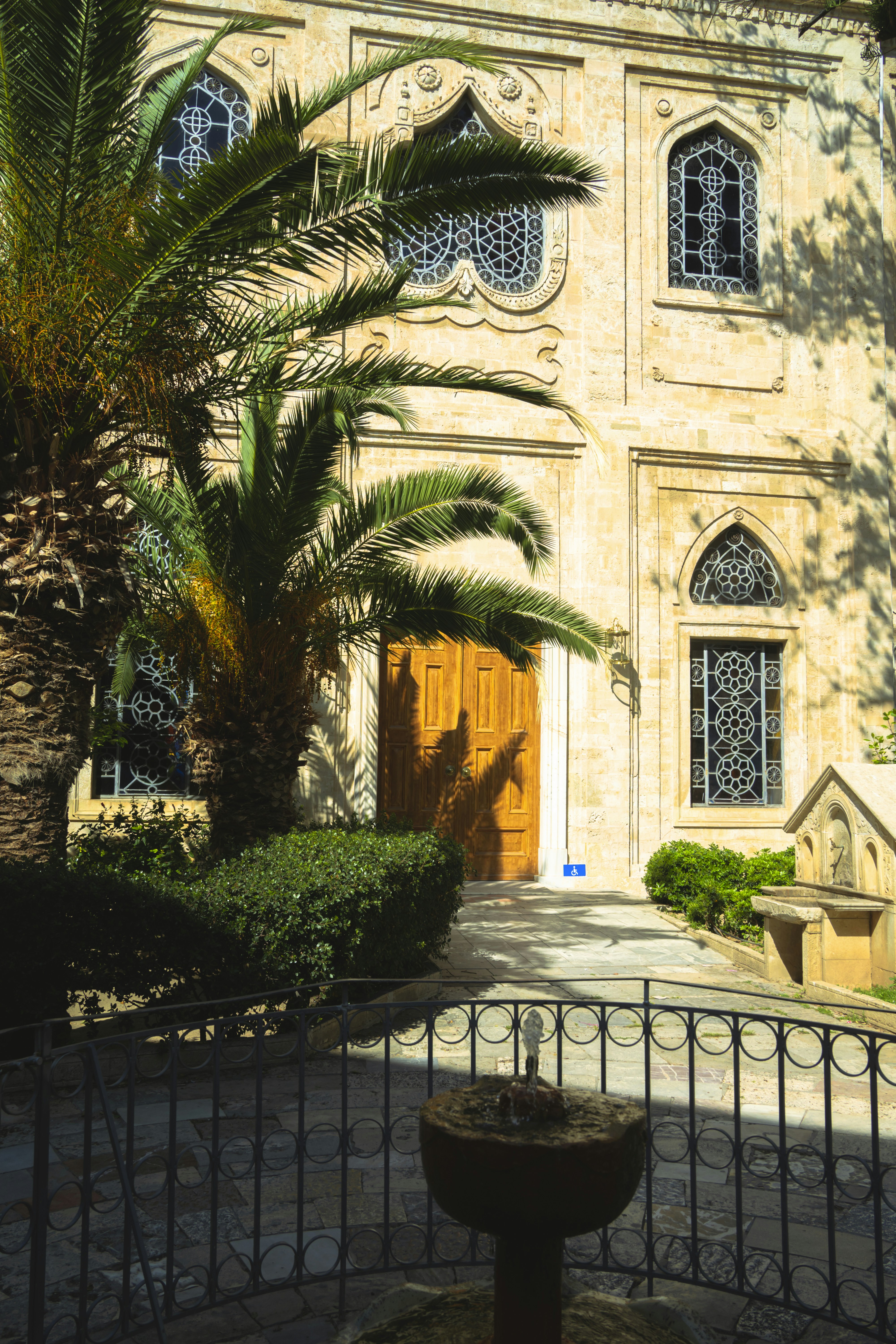 Ornate building entrance with palm trees and fountain.