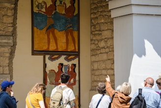 Tourists observe ancient minoan frescoes on a wall.