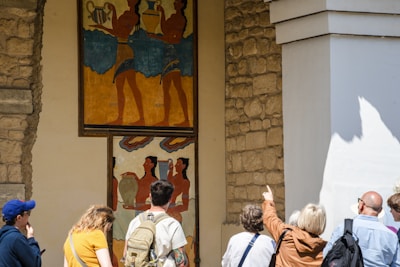 Tourists observe ancient minoan frescoes on a wall.