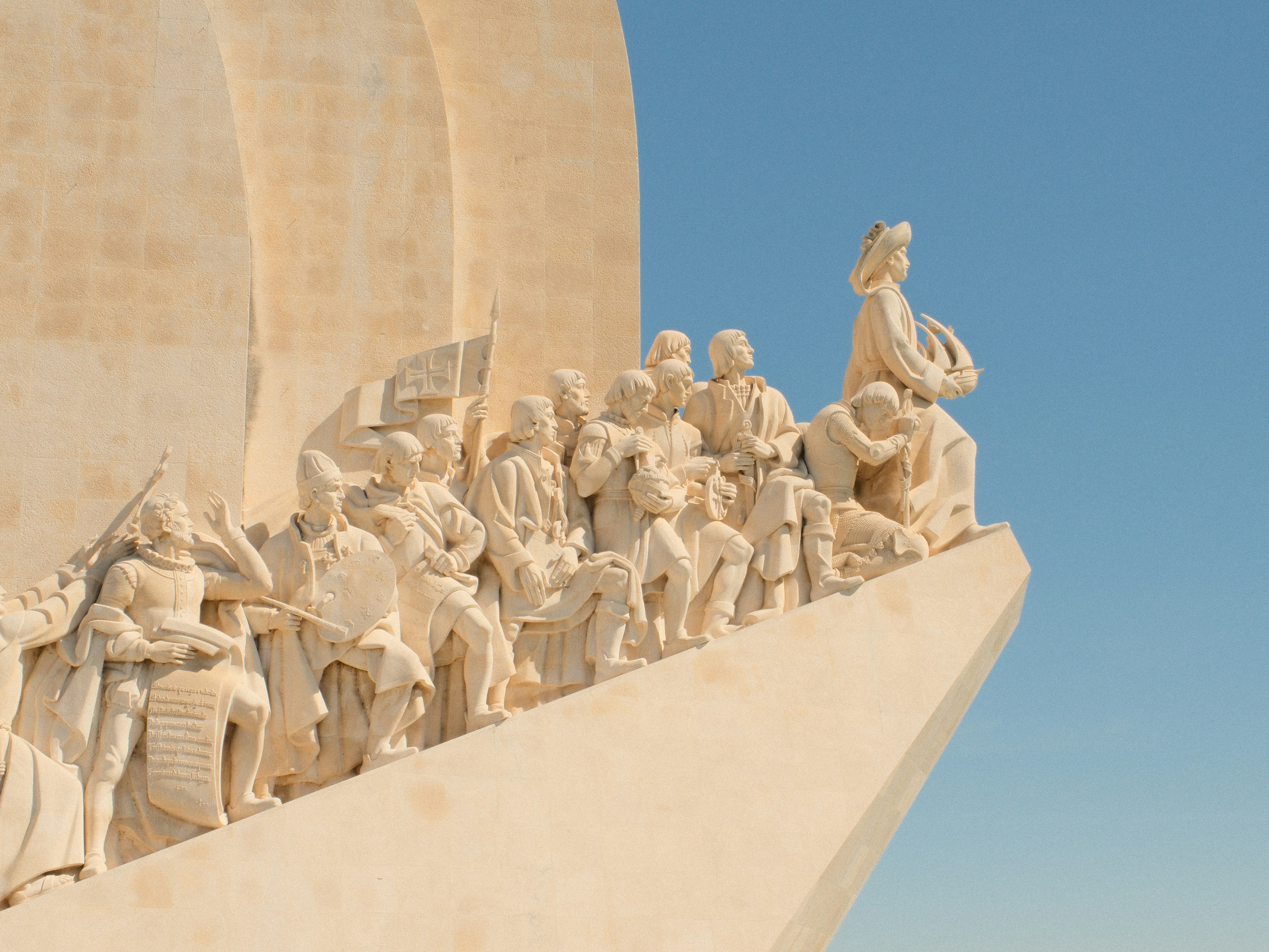 Stone monument with historical figures against blue sky